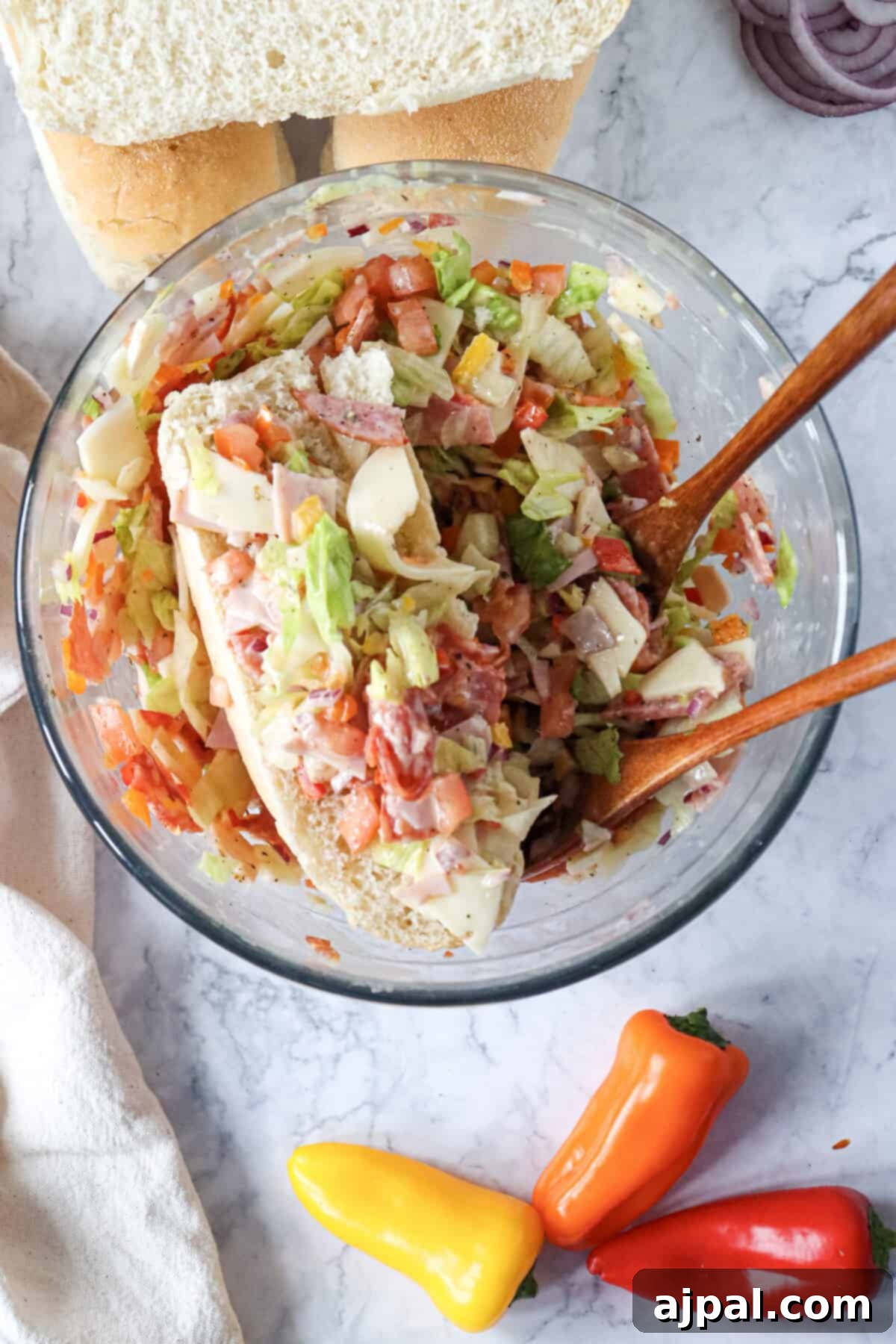 A transparent glass bowl showcasing a freshly prepared, colorful Italian salad, perfectly dressed and ready.