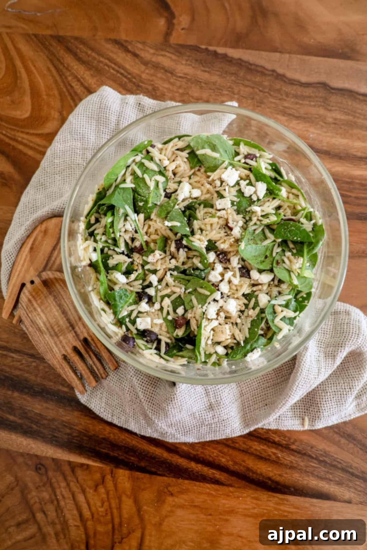 Greek Spinach Feta Orzo Salad 9 A bowl of orzo salad with feta on a wooden table.
