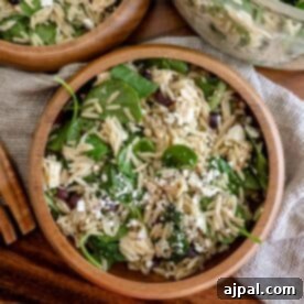Two wooden bowls filled with spinach, feta, and orzo salad, showcasing its fresh and vibrant ingredients.