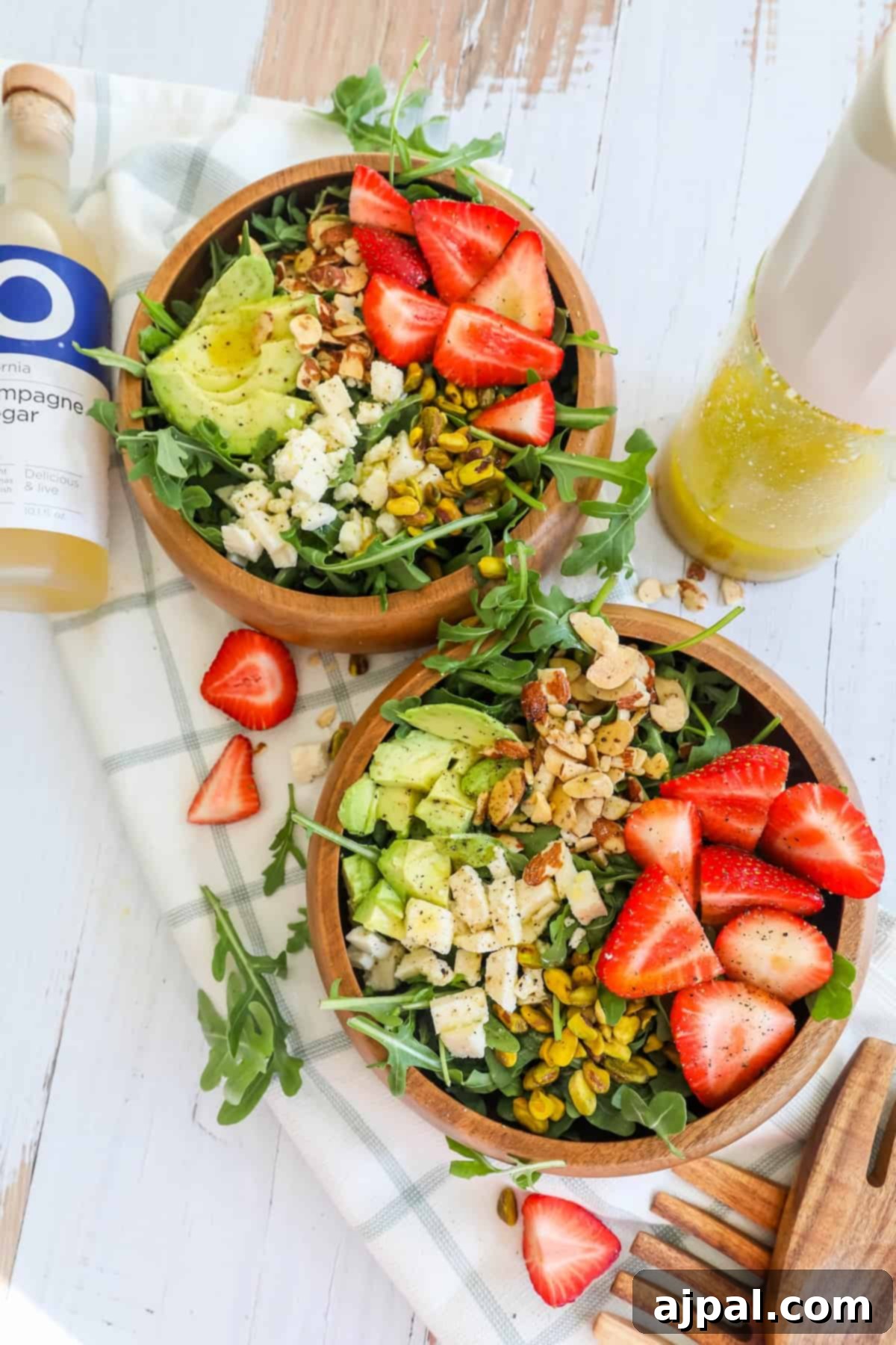 Two bowls of Strawberry Crunch Salad, garnished with fresh strawberries, crunchy nuts, and creamy feta cheese, ready to be served.