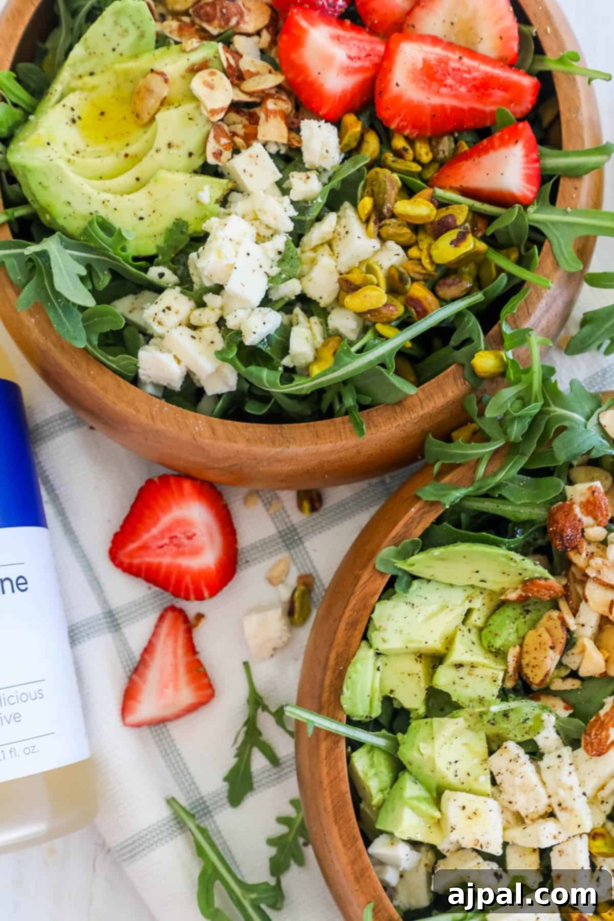Two artistic bowls filled with Strawberry Crunch Salad, featuring luscious strawberries, creamy avocado, and crunchy pistachios, ready to be enjoyed as a healthy meal.