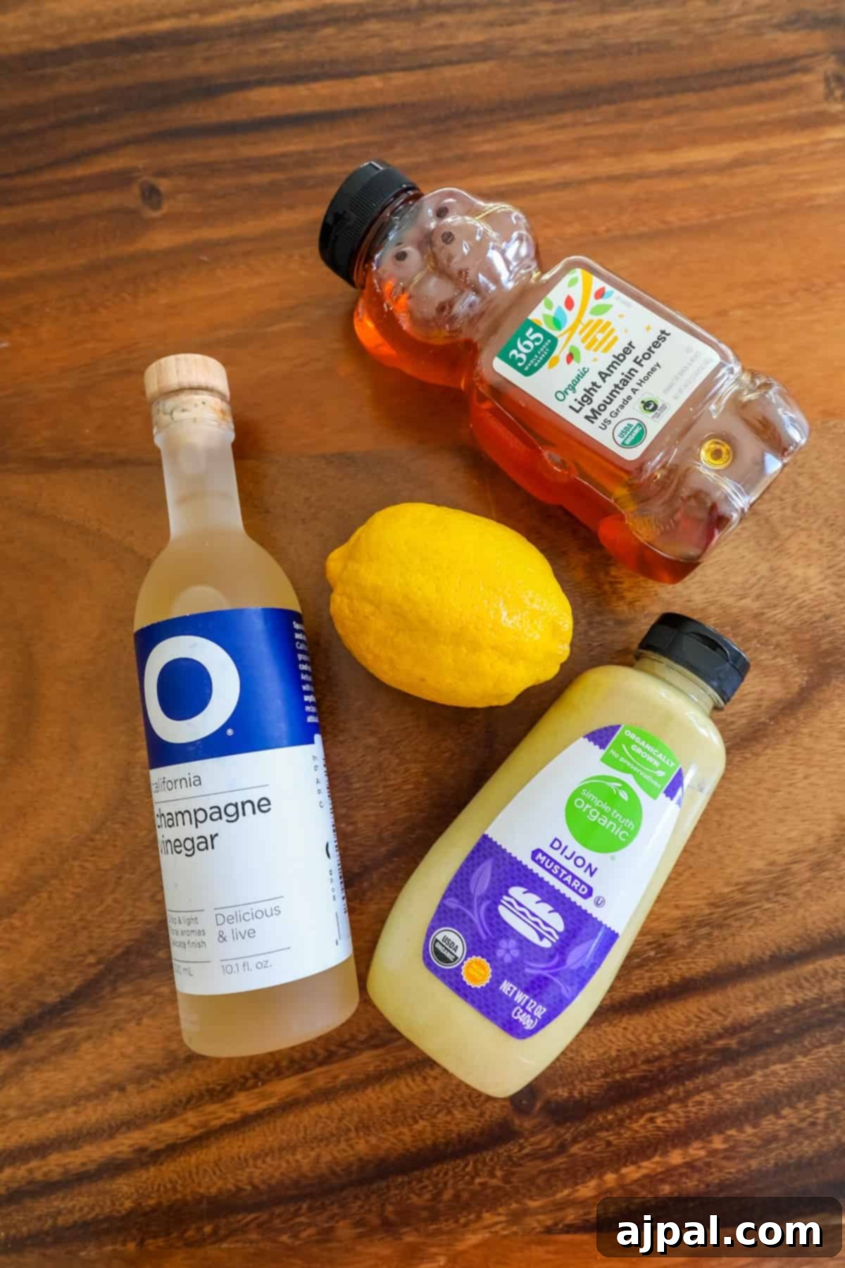 Fresh lemon juice and golden honey, key ingredients for the Champagne Vinaigrette, arranged on a rustic wooden table.