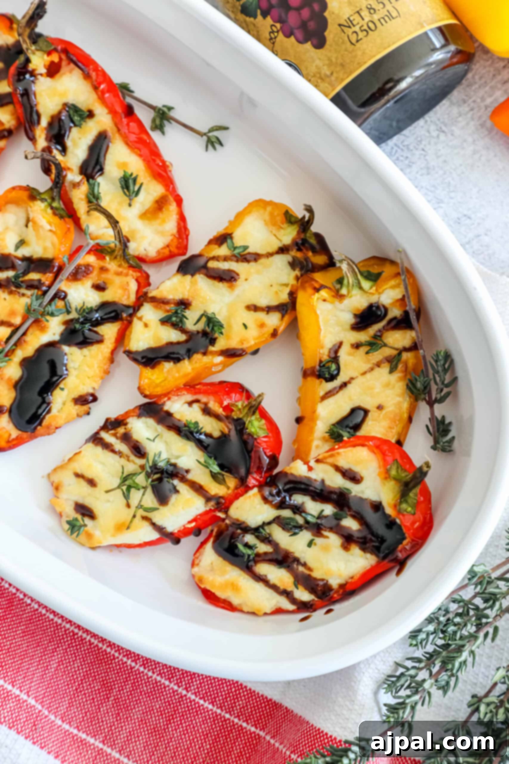 Goat Cheese Stuffed Peppers 2 A plate of colorful baked mini bell peppers generously stuffed with creamy goat cheese, drizzled with glossy balsamic glaze, and garnished with fresh herbs, ready to be served.