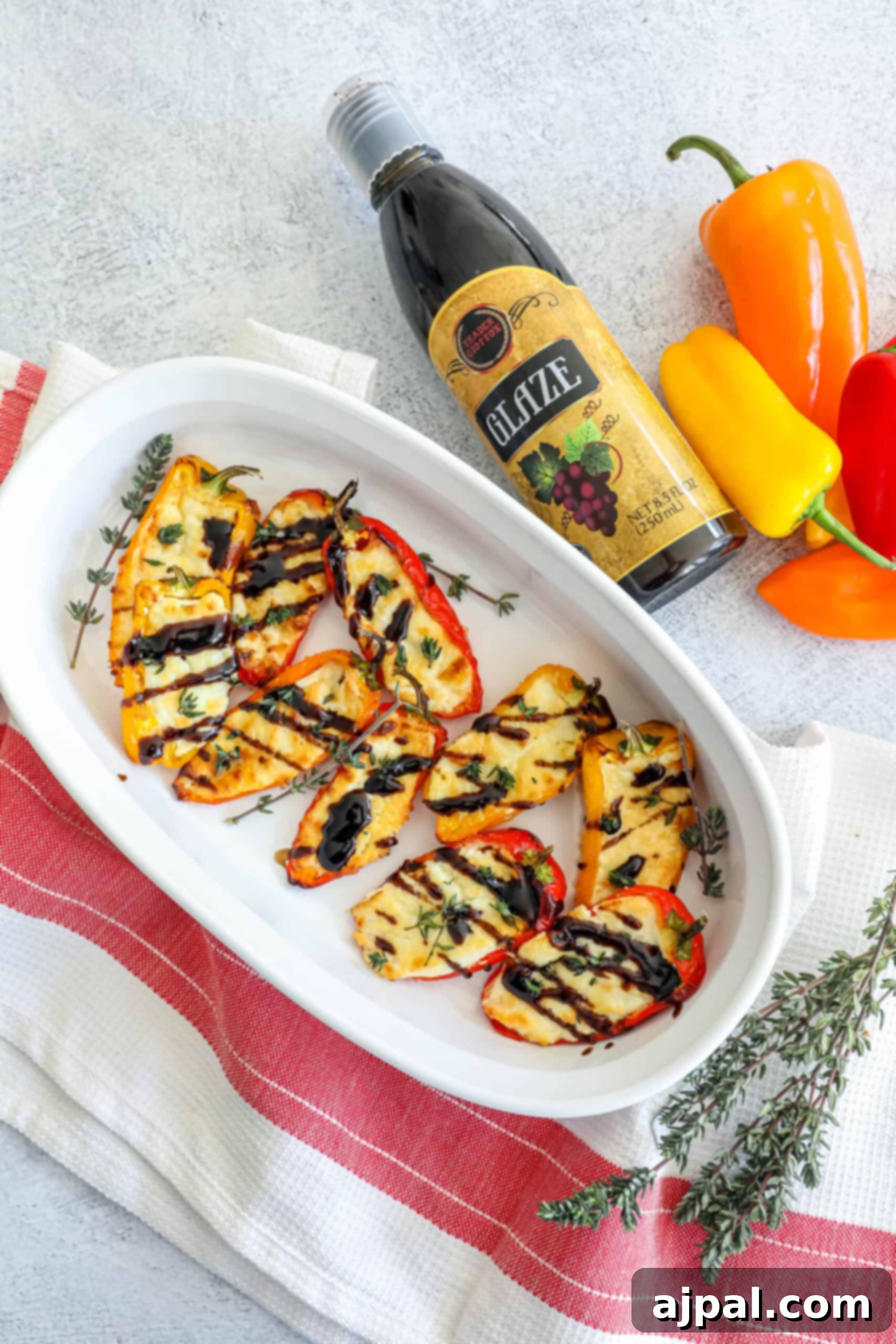 Goat Cheese Stuffed Peppers 11 A elegant white dish showcasing baked goat cheese peppers, perfectly golden and drizzled with a rich balsamic glaze, presented next to a bottle of wine, hinting at a gourmet dining experience.