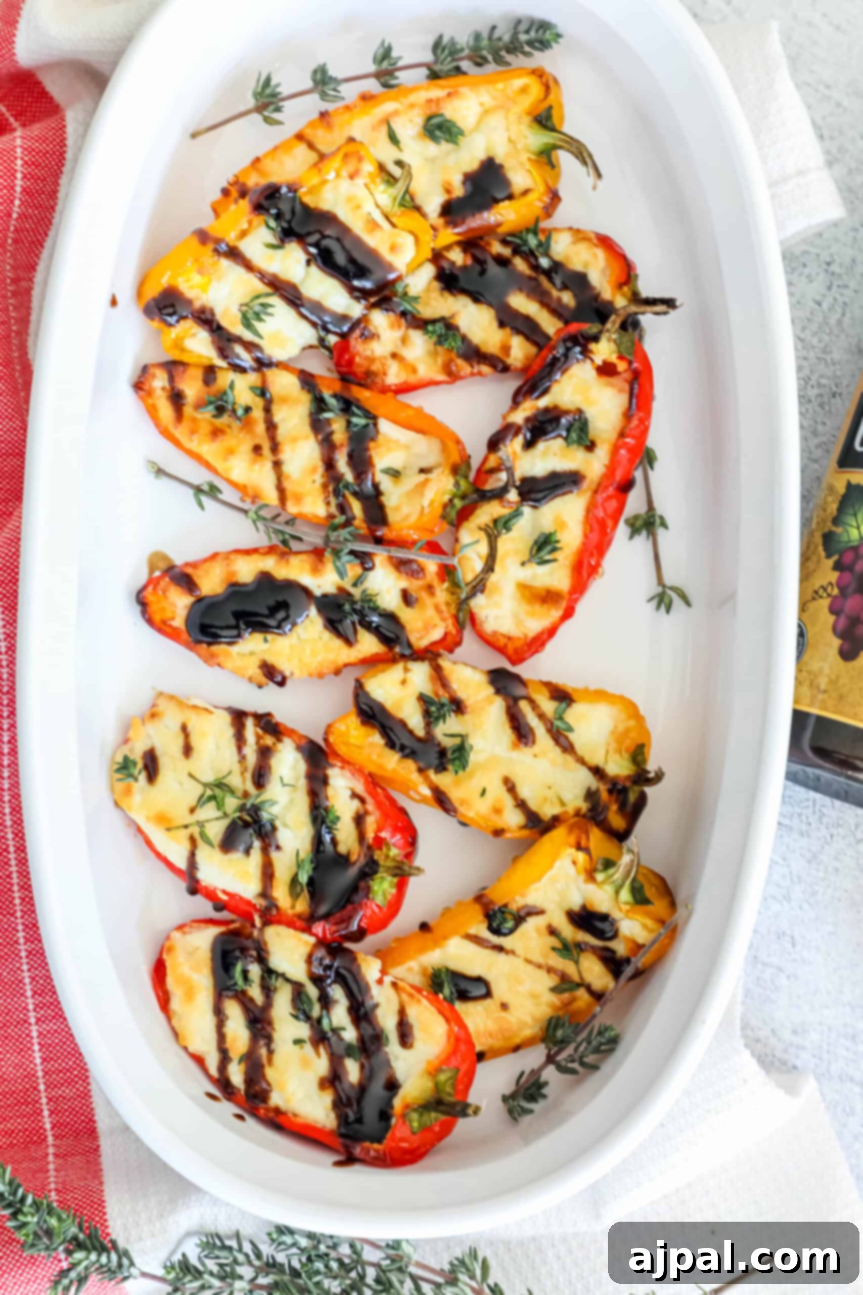 Goat Cheese Stuffed Peppers 3 A white baking dish filled with beautifully baked mini bell peppers, each overflowing with golden-brown goat cheese and sprinkled with fresh green herbs, ready to be served.