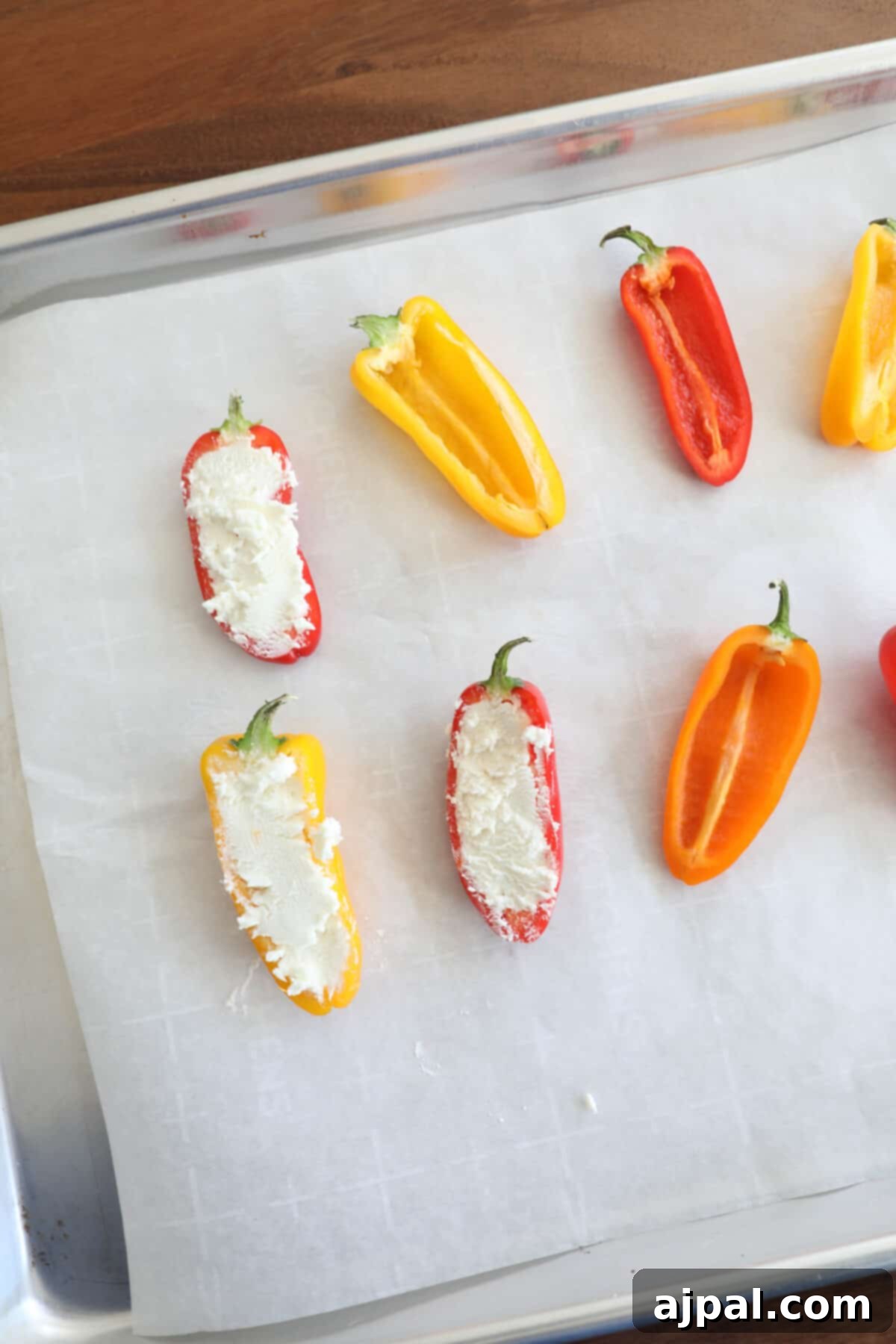 Goat Cheese Stuffed Peppers 6 A close-up shot of raw mini bell peppers, neatly halved and deseeded, ready to be stuffed, laid out on a baking sheet before filling.