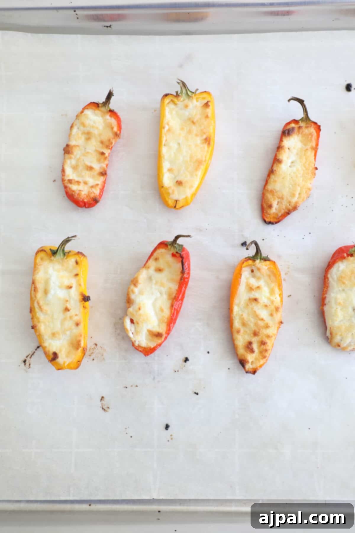 Goat Cheese Stuffed Peppers 8 A baking sheet filled with golden-brown baked goat cheese peppers, just out of the oven, with the cheese slightly bubbly and the pepper edges lightly charred.