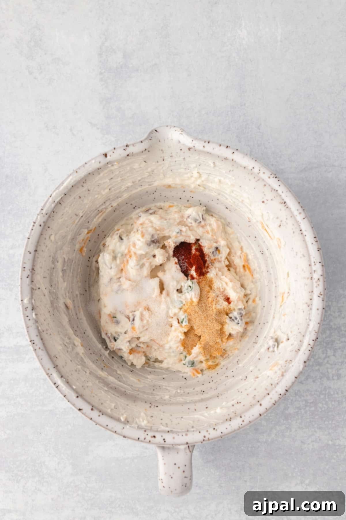 Grand Occasion Dip 8 A rustic bowl of creamy hummus, a perfect appetizer, rests on a subtly textured grey background.