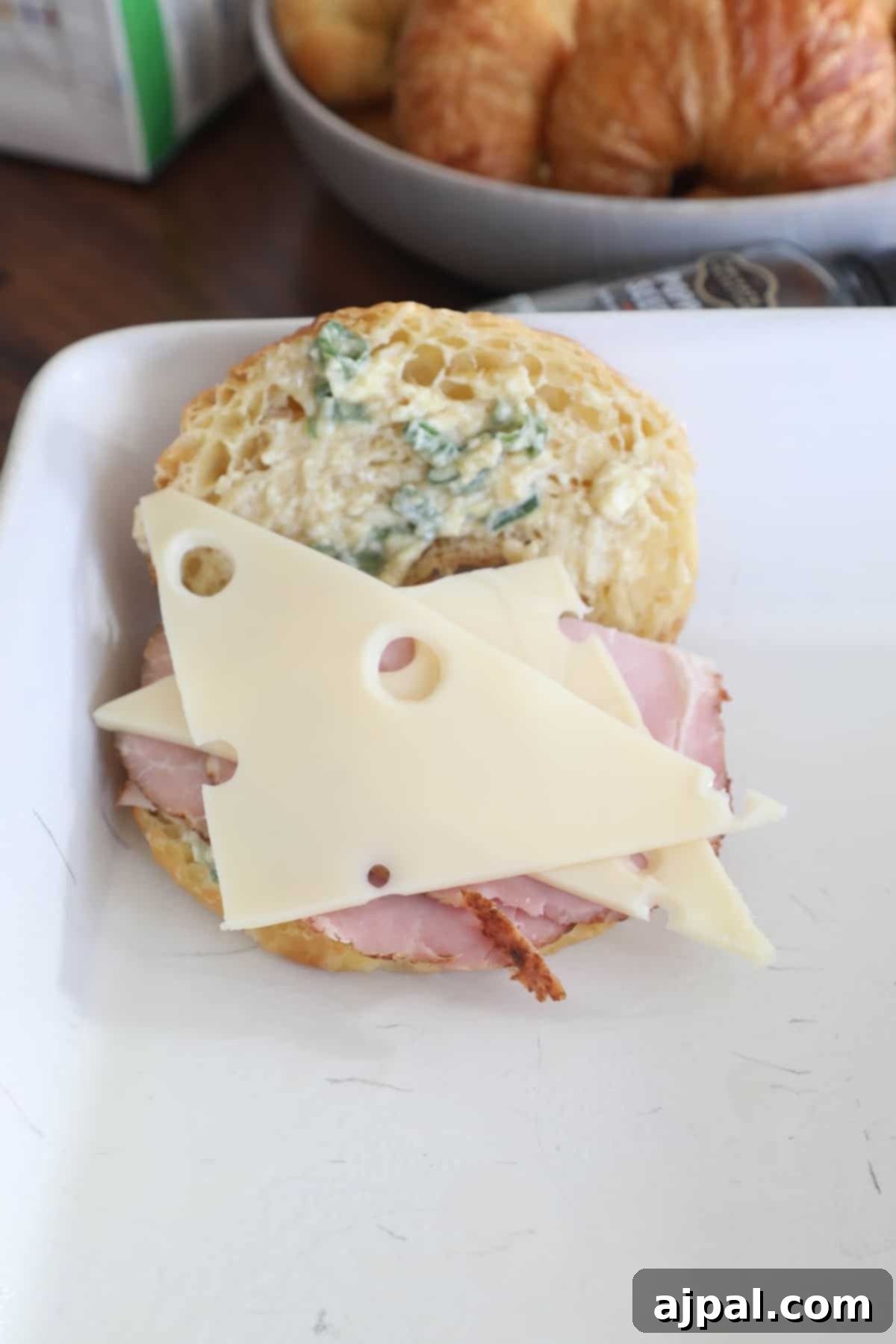 Warm Ham and Cheese Croissant Melts 11 A croissant sandwich filled with ham and cheese on a plate, demonstrating adding fillings.