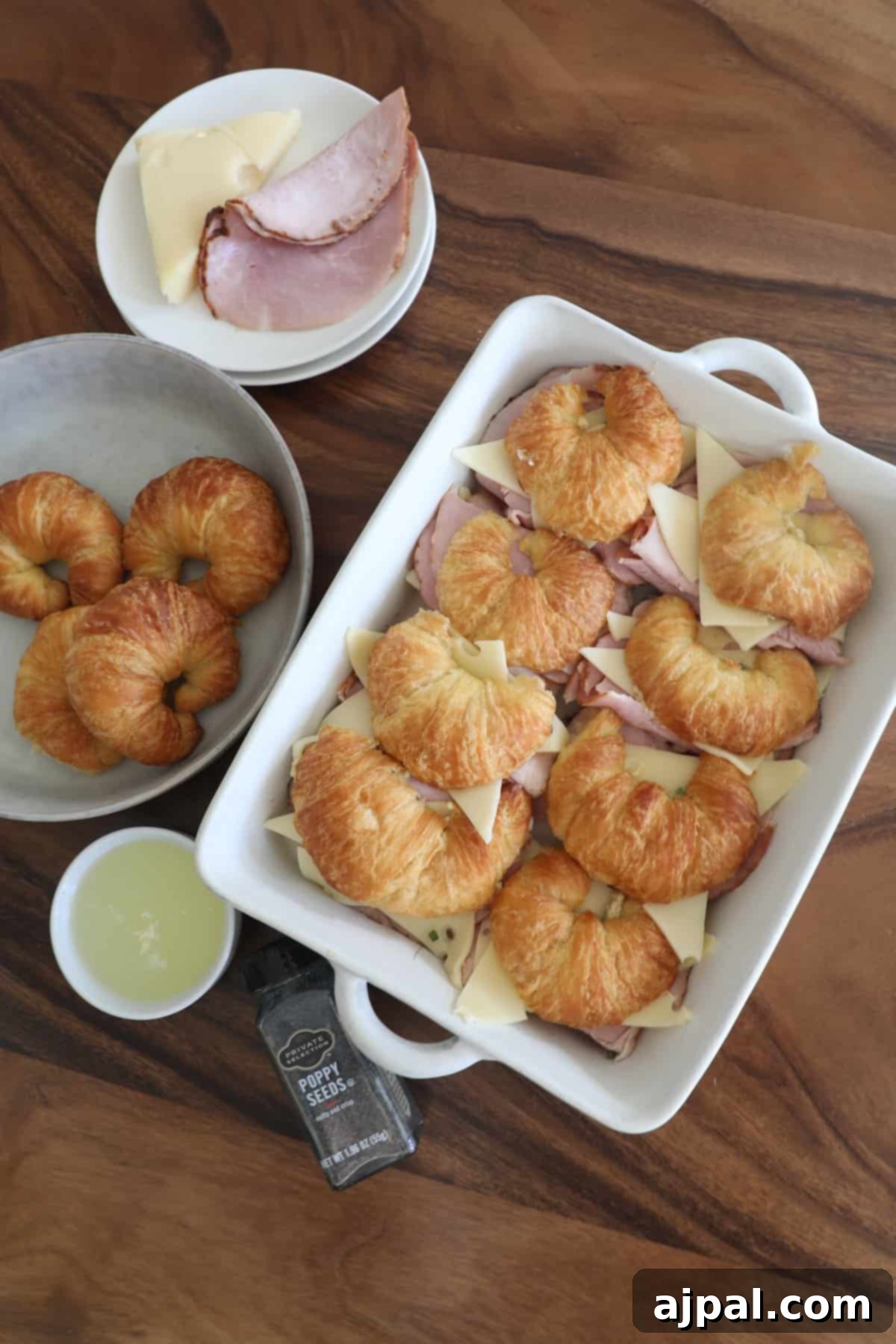 Warm Ham and Cheese Croissant Melts 12 A plate with croissants, ham, and cheese ingredients on a table, illustrating whisking the topping.