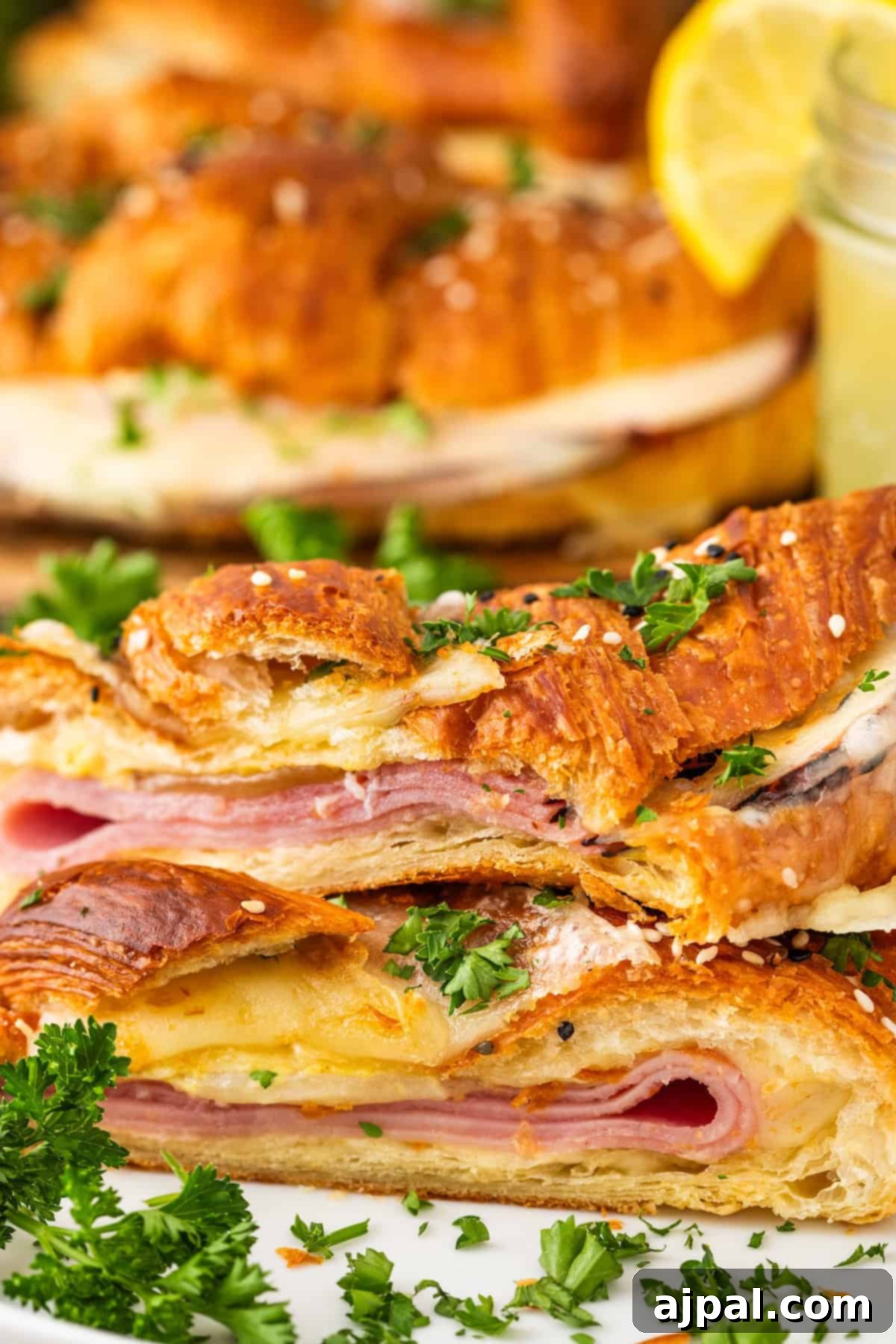 Warm Ham and Cheese Croissant Melts 4 Baked ham and cheese croissant with ham and cheese filling, garnished with chopped parsley and a lemon wedge.