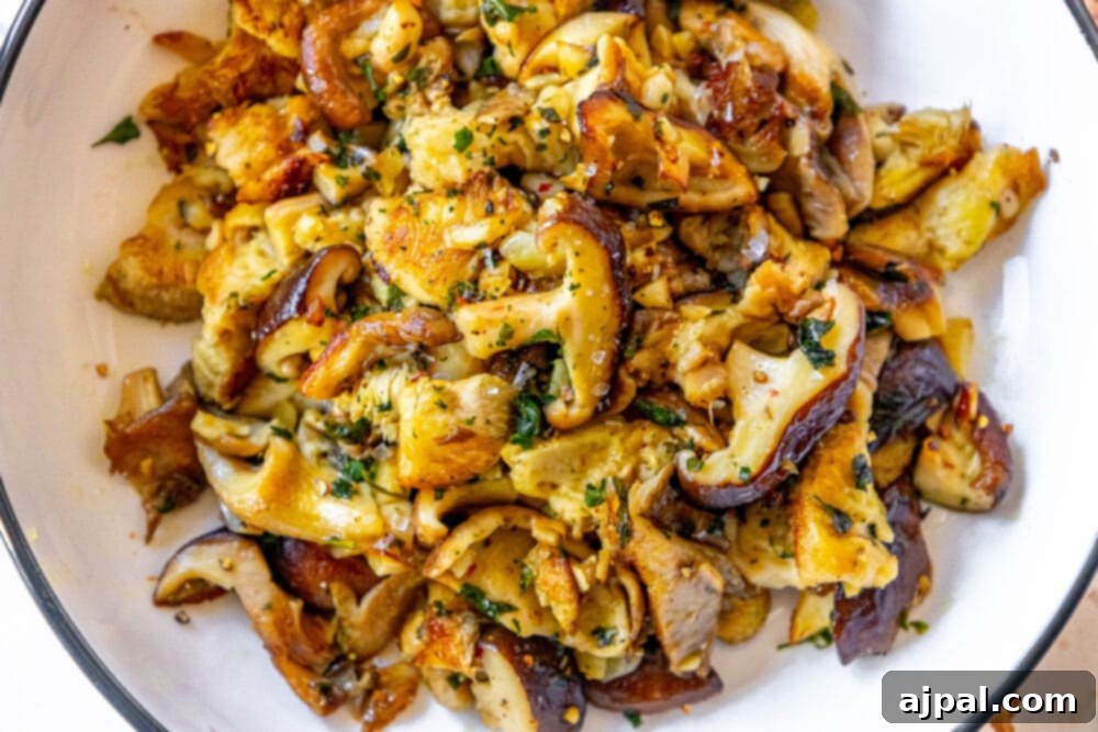 Perfect sautéed mushrooms plated with herbs and served on a white dish.