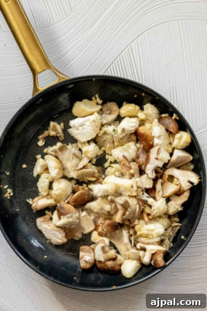 picture of chopped mushrooms in a pan with diced garlic