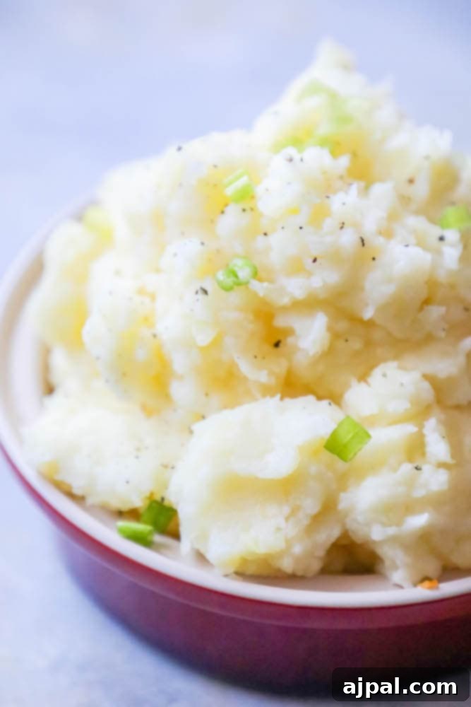 Creamy Slow Cooker Mashed Potatoes 2 mashed potatoes with green onions in a white bowl