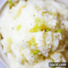 Creamy Slow Cooker Mashed Potatoes 6 A bowl of slow cooker mashed potatoes topped with chopped green onions and black pepper.