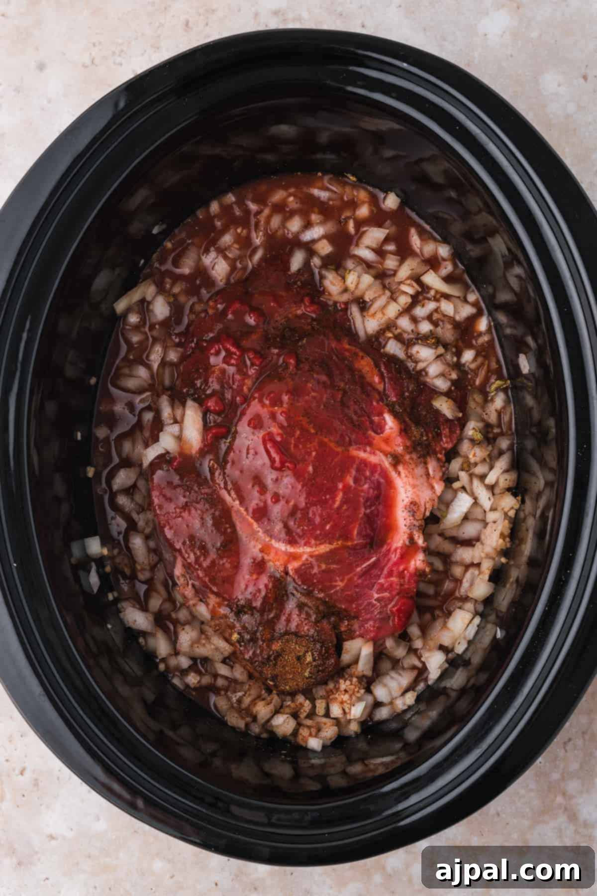 Tender Braised Beef Tacos 8 Beef tacos with shredded beef and chopped onions in a slow cooker, ready to cook.