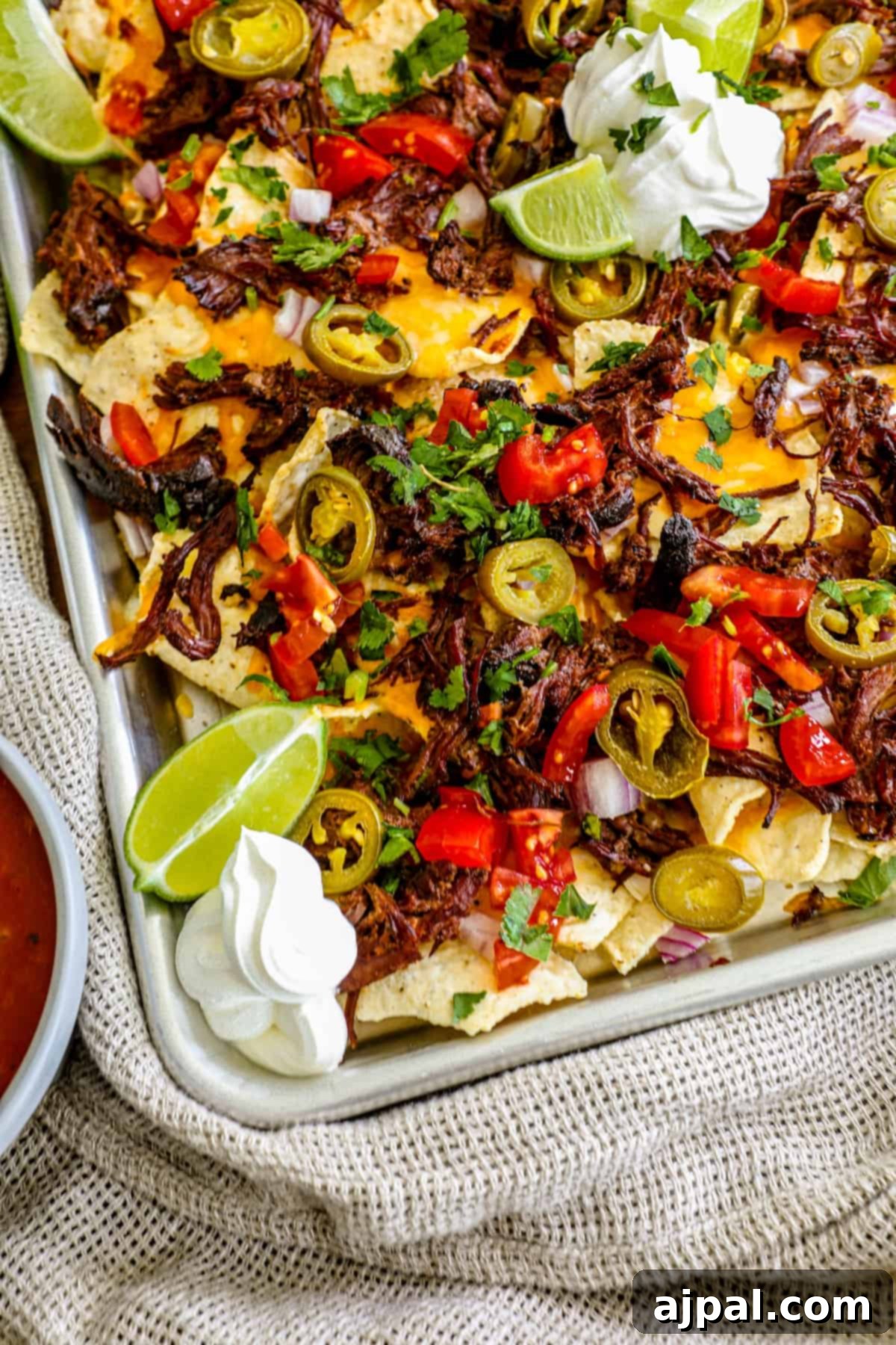 Loaded Carne Asada Nachos 4 A serving of freshly baked carne asada nachos, showing the golden melted cheese and vibrant toppings before serving.