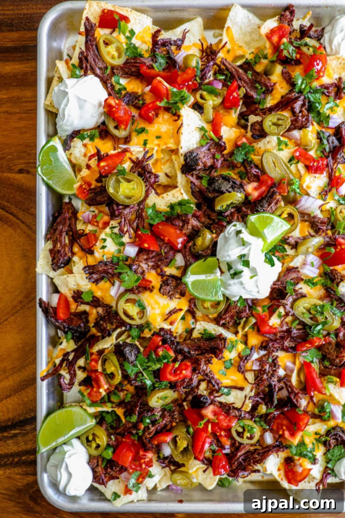 Loaded Carne Asada Nachos 5 A generous serving of carne asada nachos, garnished with fresh cilantro and a squeeze of lime.