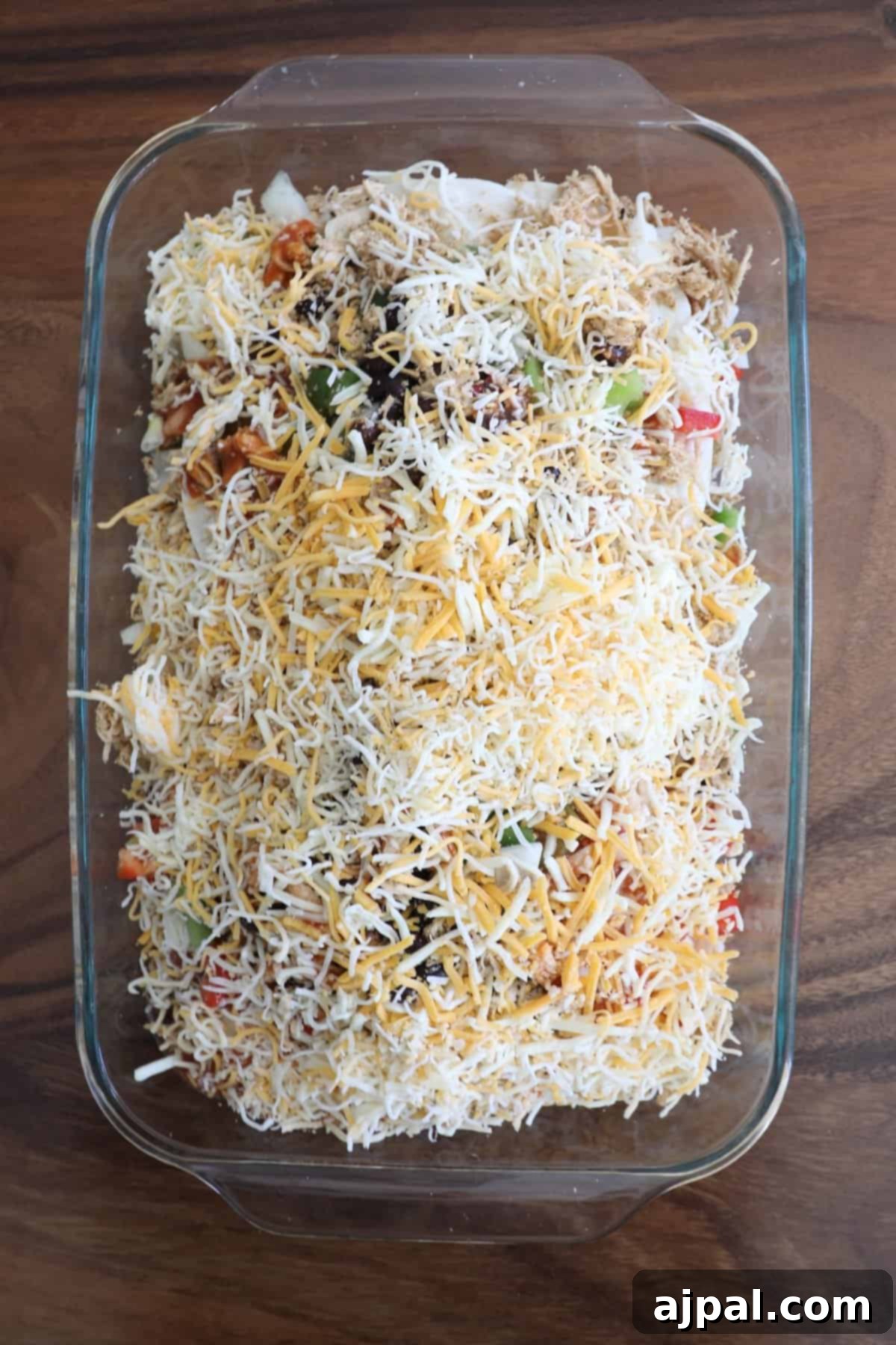 Half of the enchilada sauce and shredded cheese added over the chicken and vegetable layers.