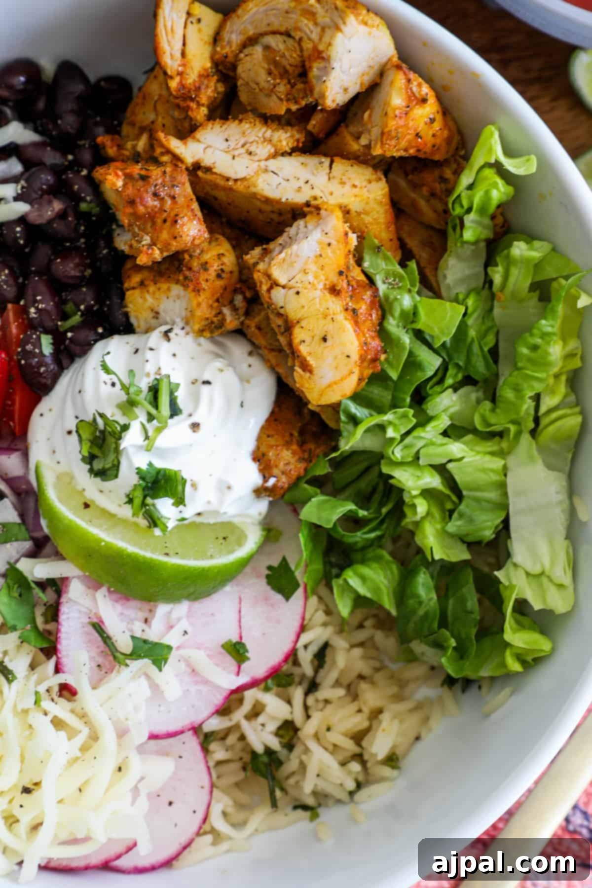 Flavorful Chicken Burrito Bowls 2 chicken, lettuce, black beans, tomatoes, lime, and sour cream in a bowl