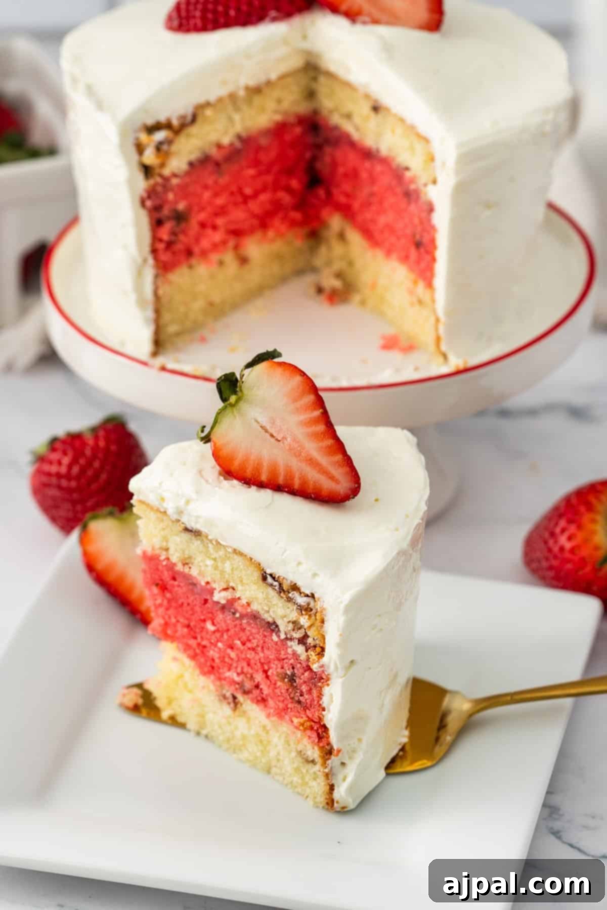 Two-layer vanilla cake with one strawberry layer in the middle, frosted with white cream and topped with a fresh strawberry.