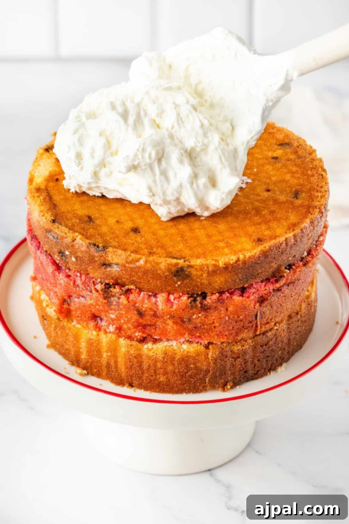 Three-layer cake partially frosted with white cream, showcasing the layers.