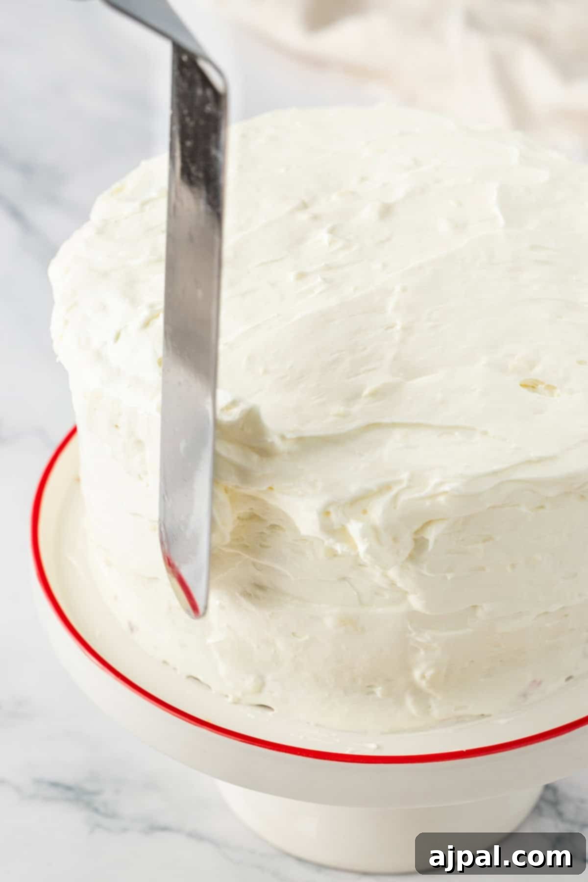 Cake being iced with a spatula, showing the process of frosting.