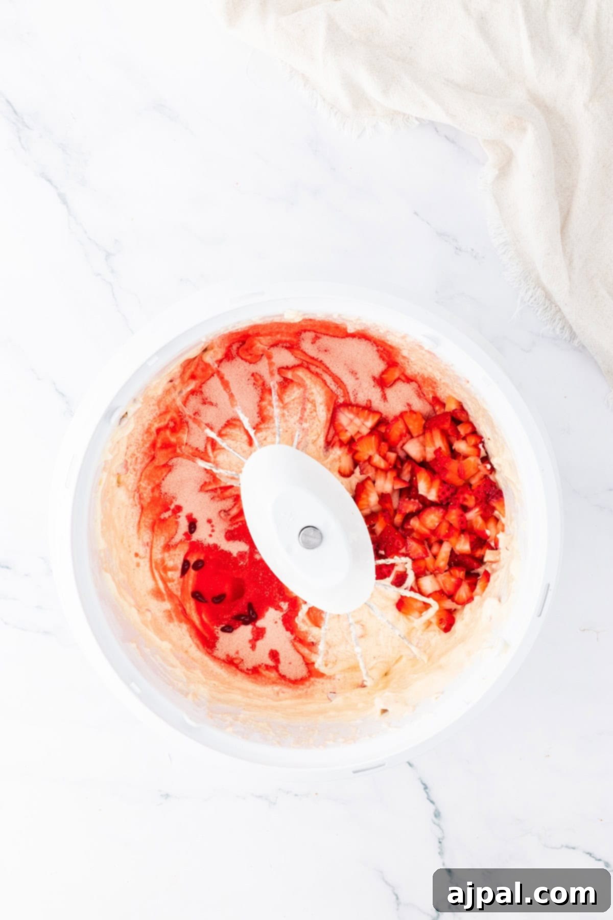 Close-up of a bowl with strawberries mixed into the cake batter, highlighting the fresh fruit.