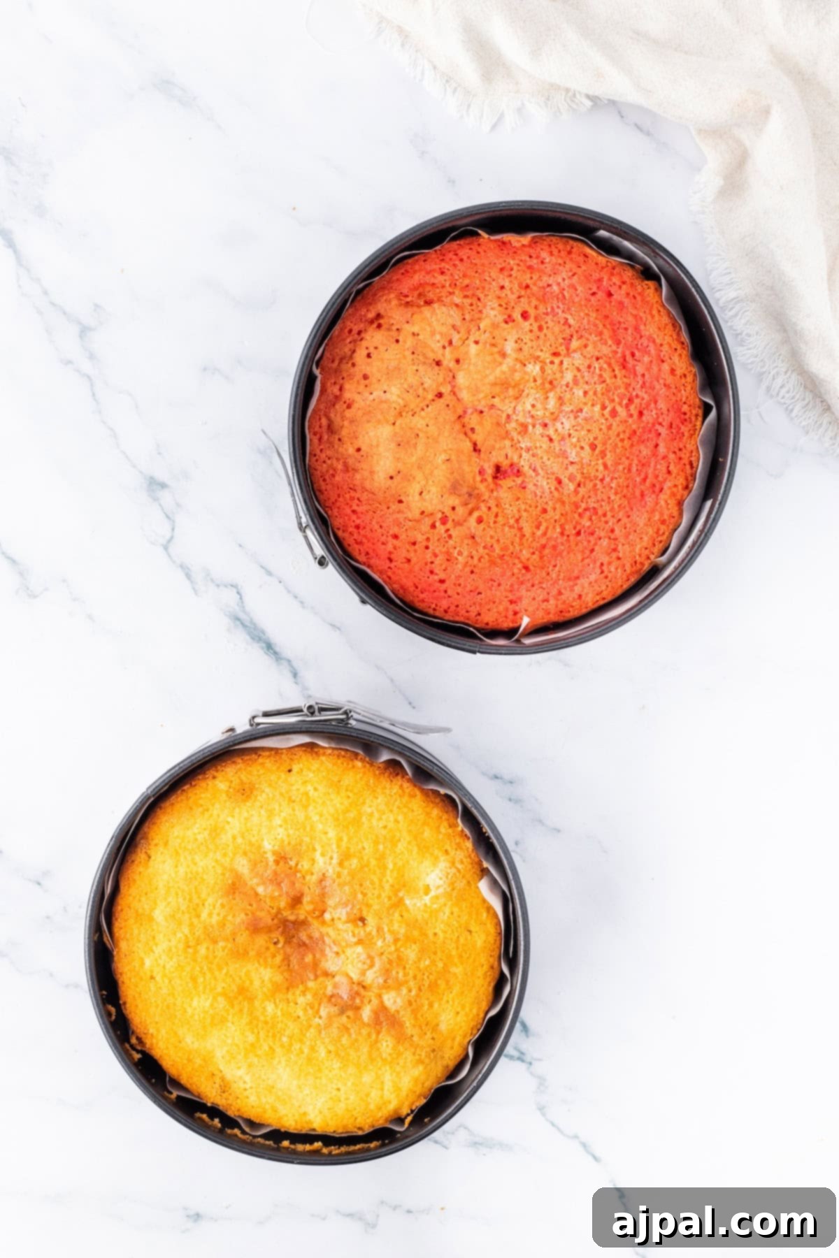 Two baked cake layers cooling in their pans after being removed from the oven.
