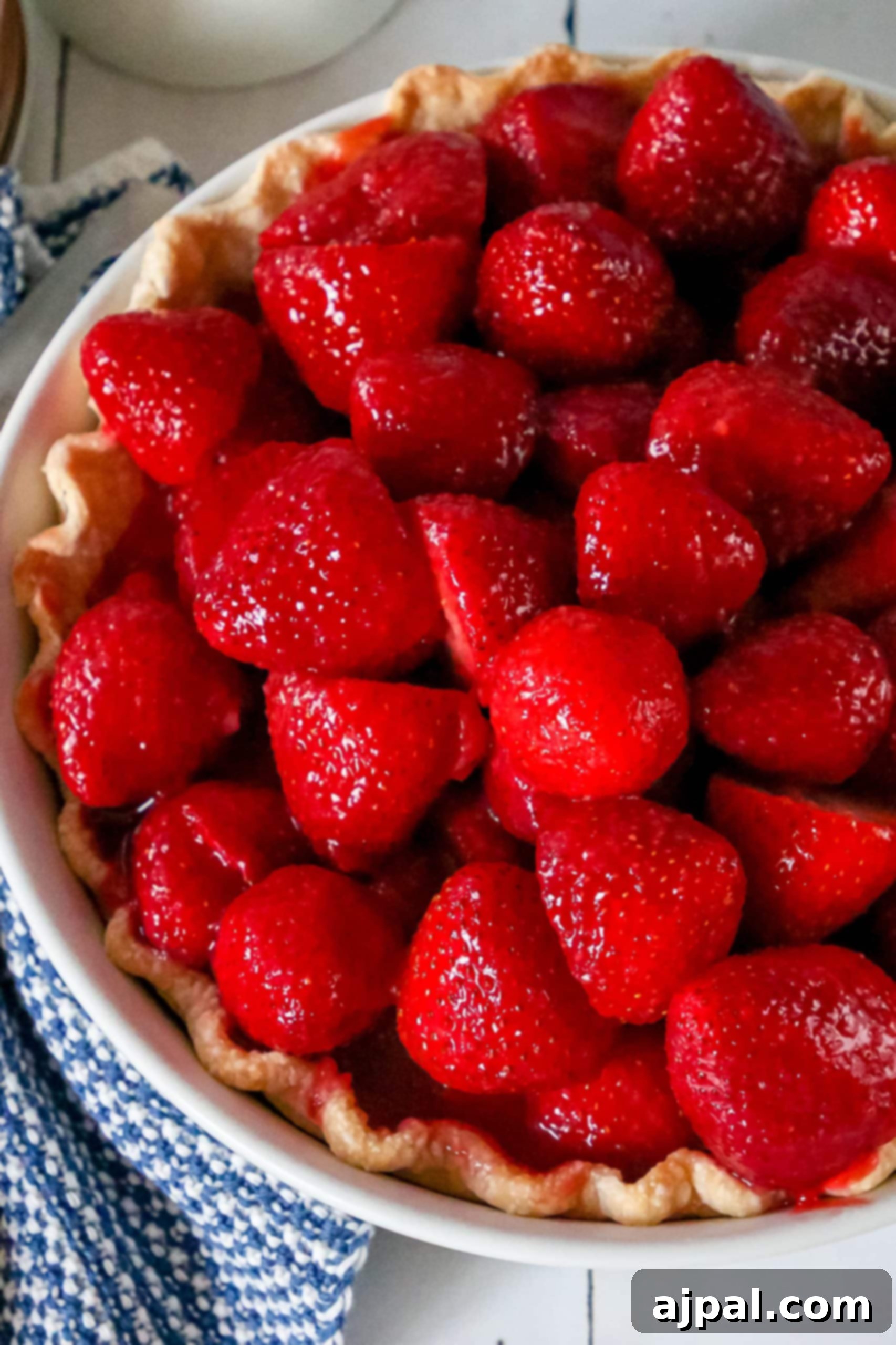 Sweet Summer Strawberry Pie 4 A slice of easy strawberry pie recipe on a pristine white plate, accompanied by a neatly folded blue napkin.