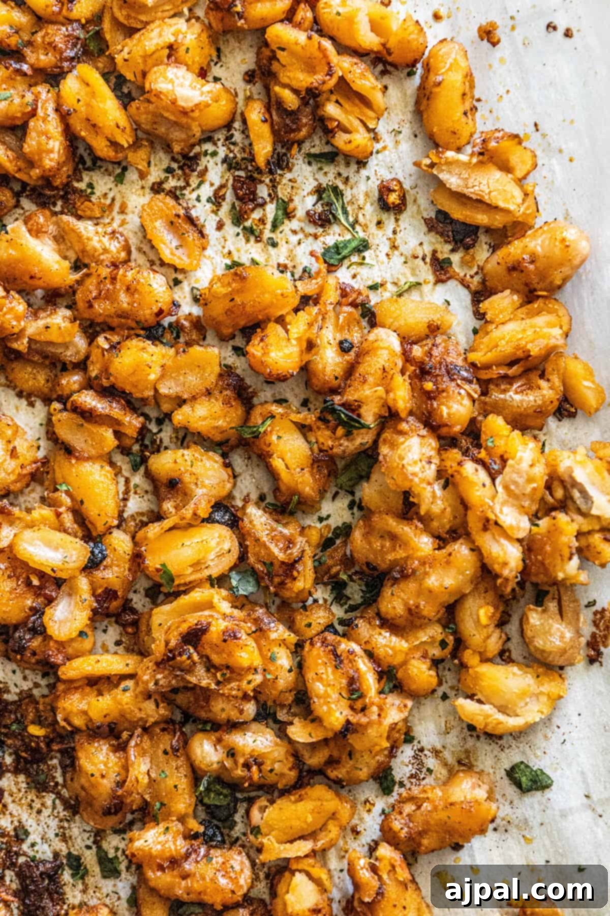 A bowl of vibrant, golden-brown roasted white beans, glistening with chili crisp, inviting a closer look at their crispy texture and spicy coating.