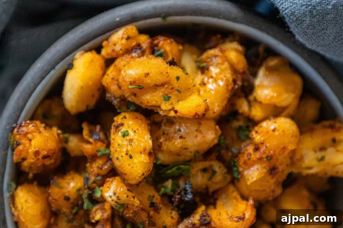 A serving of crispy roasted white beans generously coated in chili crisp, garnished with fresh herbs, ready to be devoured as a spicy, savory snack.