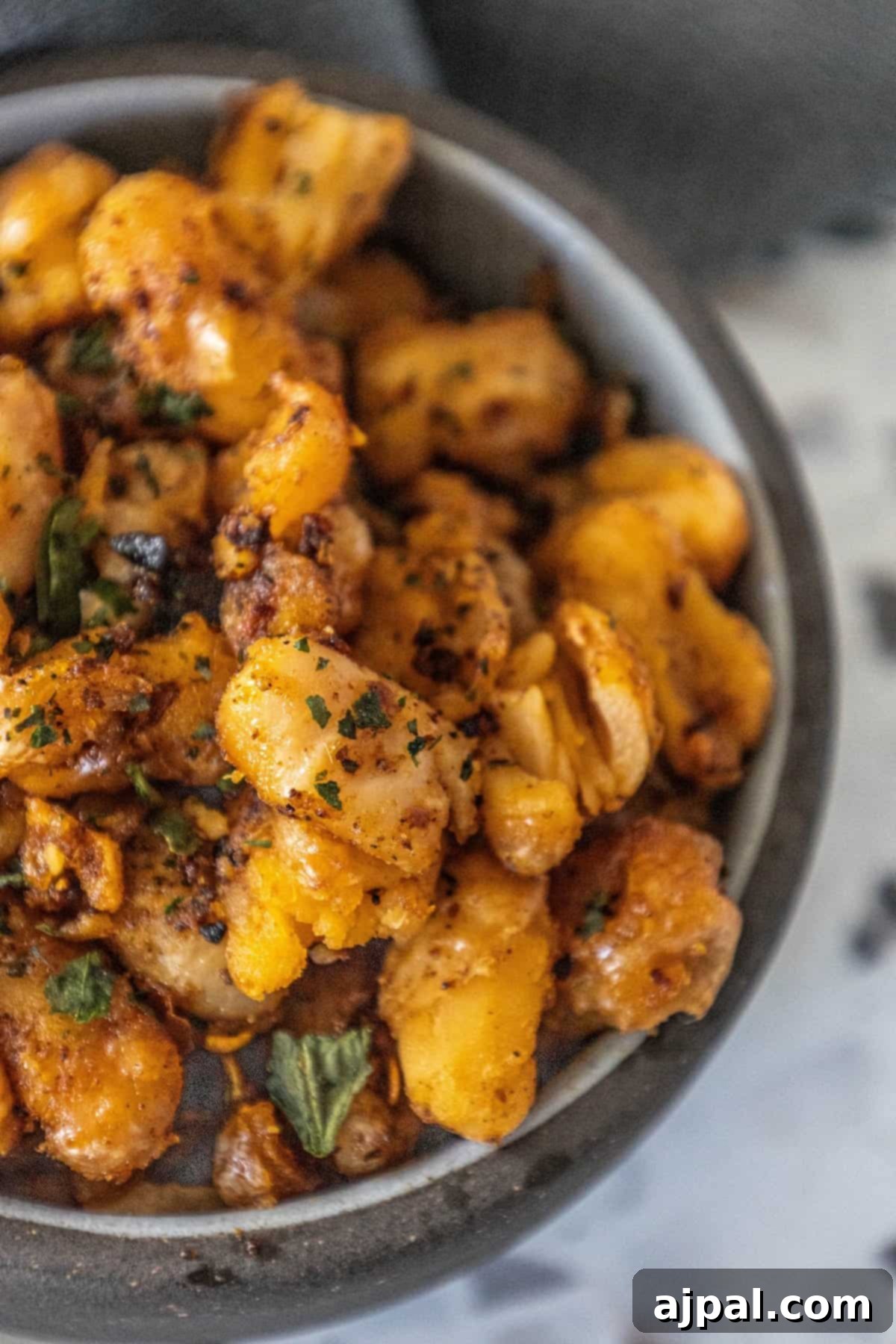 A bowl overflowing with crispy roasted white beans and chili crisp, highlighting the generous amount of savory, spicy topping and the perfect golden texture of the beans.