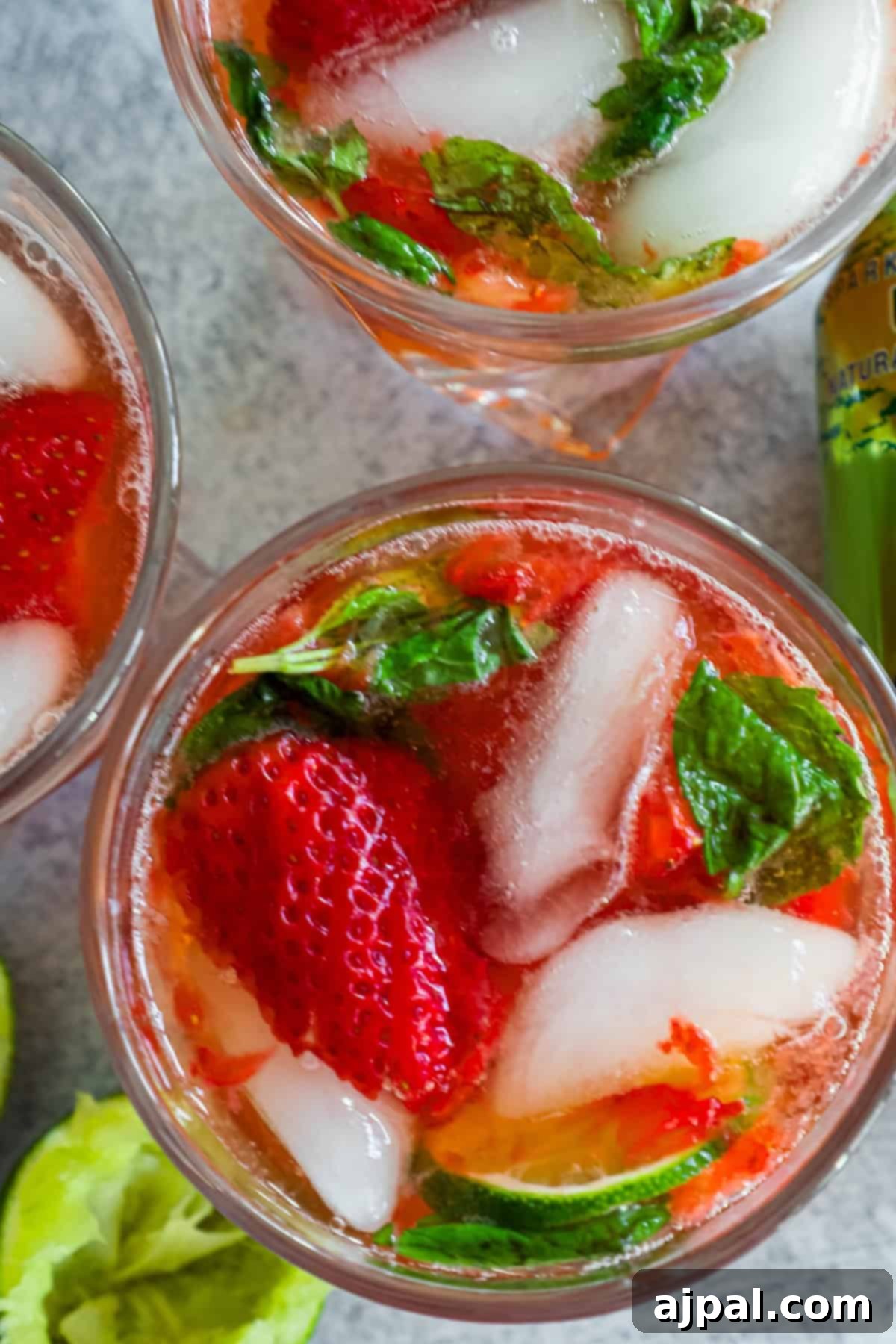 Three glasses of strawberry mojitos with fresh mint leaves, viewed from above, highlighting the vibrant colors and fresh garnishes.