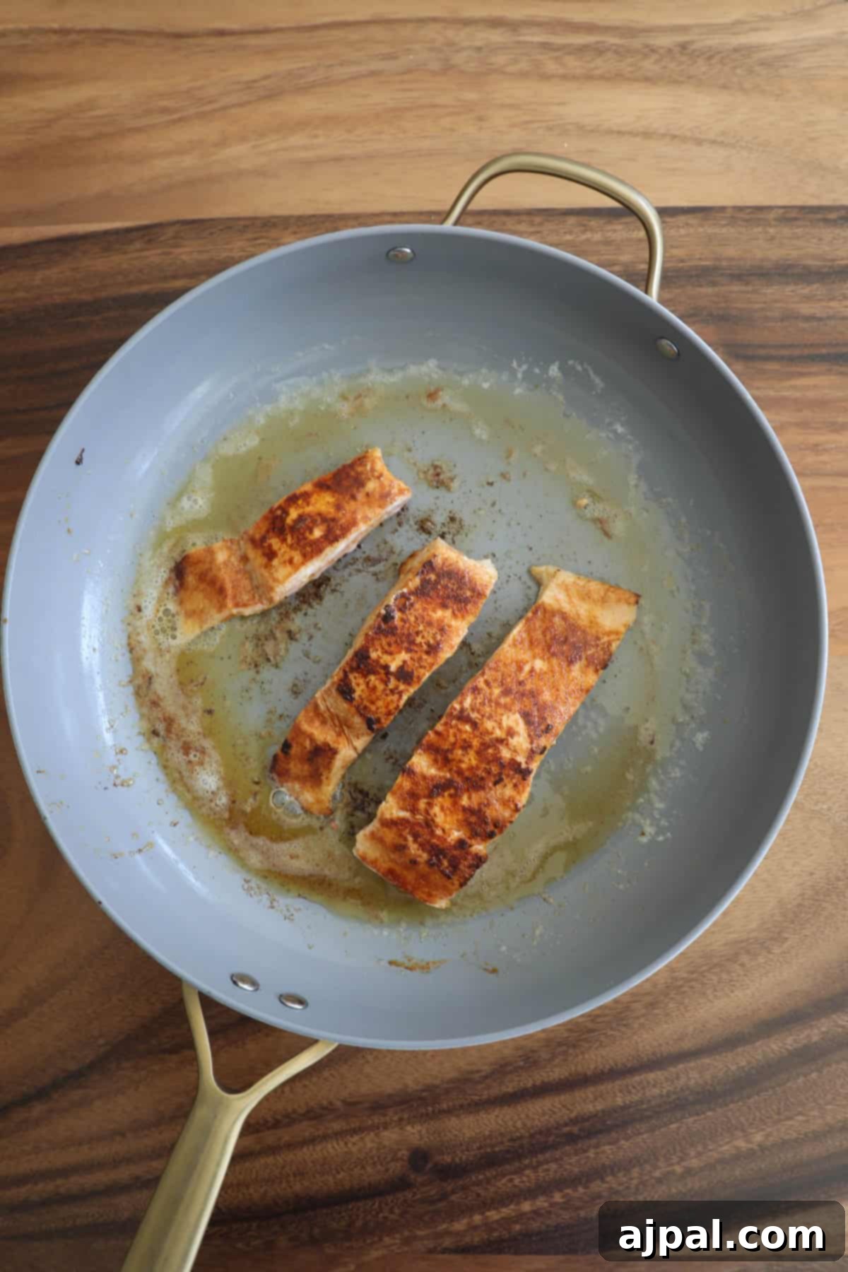 Creamy Salmon Florentine Orzo 6 Two slices of grilled chicken breast in a frying pan, cooking on a wooden kitchen counter.