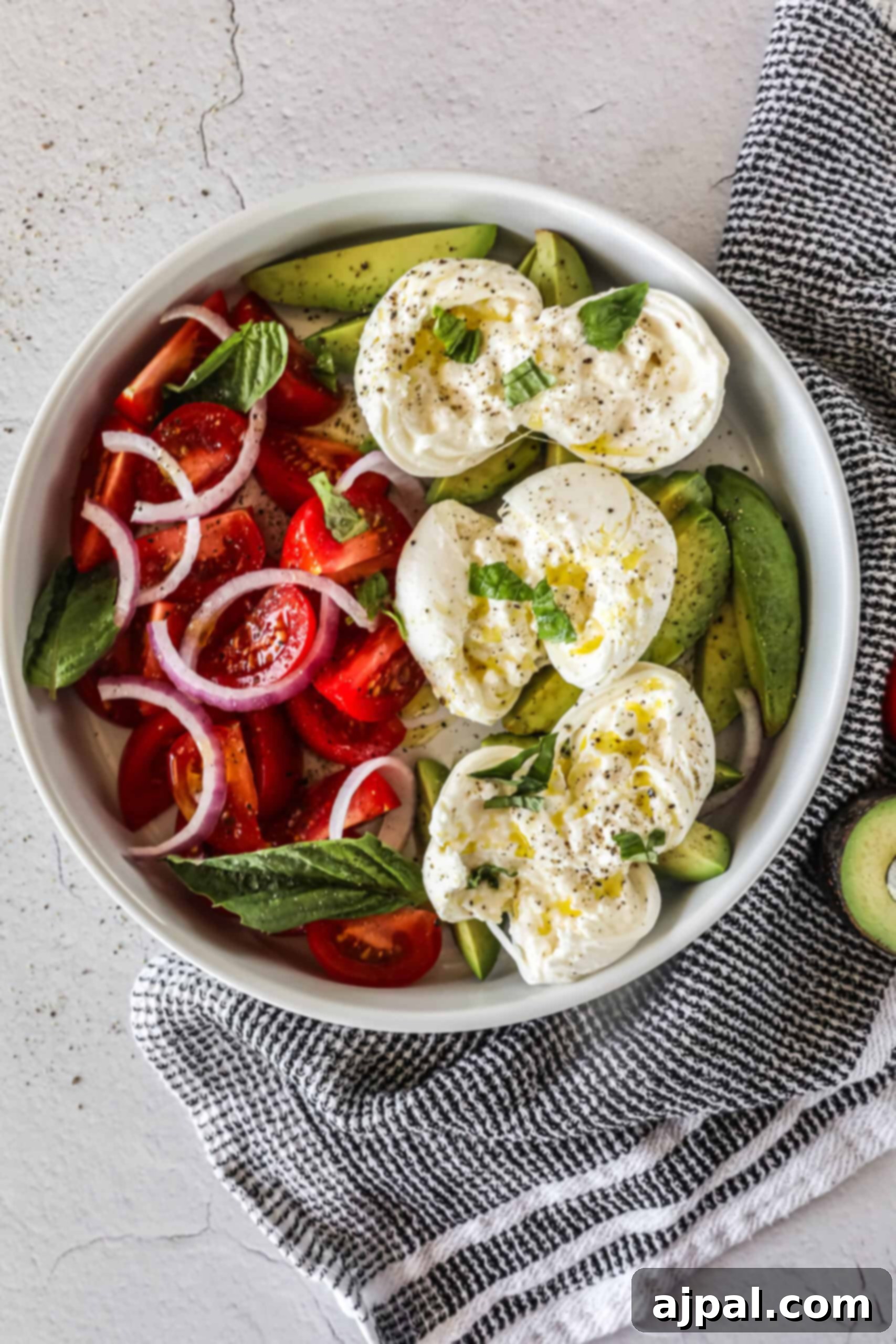 Creamy Burrata Avocado Tomato Salad 3 Close-up of fresh burrata cheese, partially broken to reveal its creamy interior, surrounded by colorful tomatoes and ripe avocado, ready for dressing.