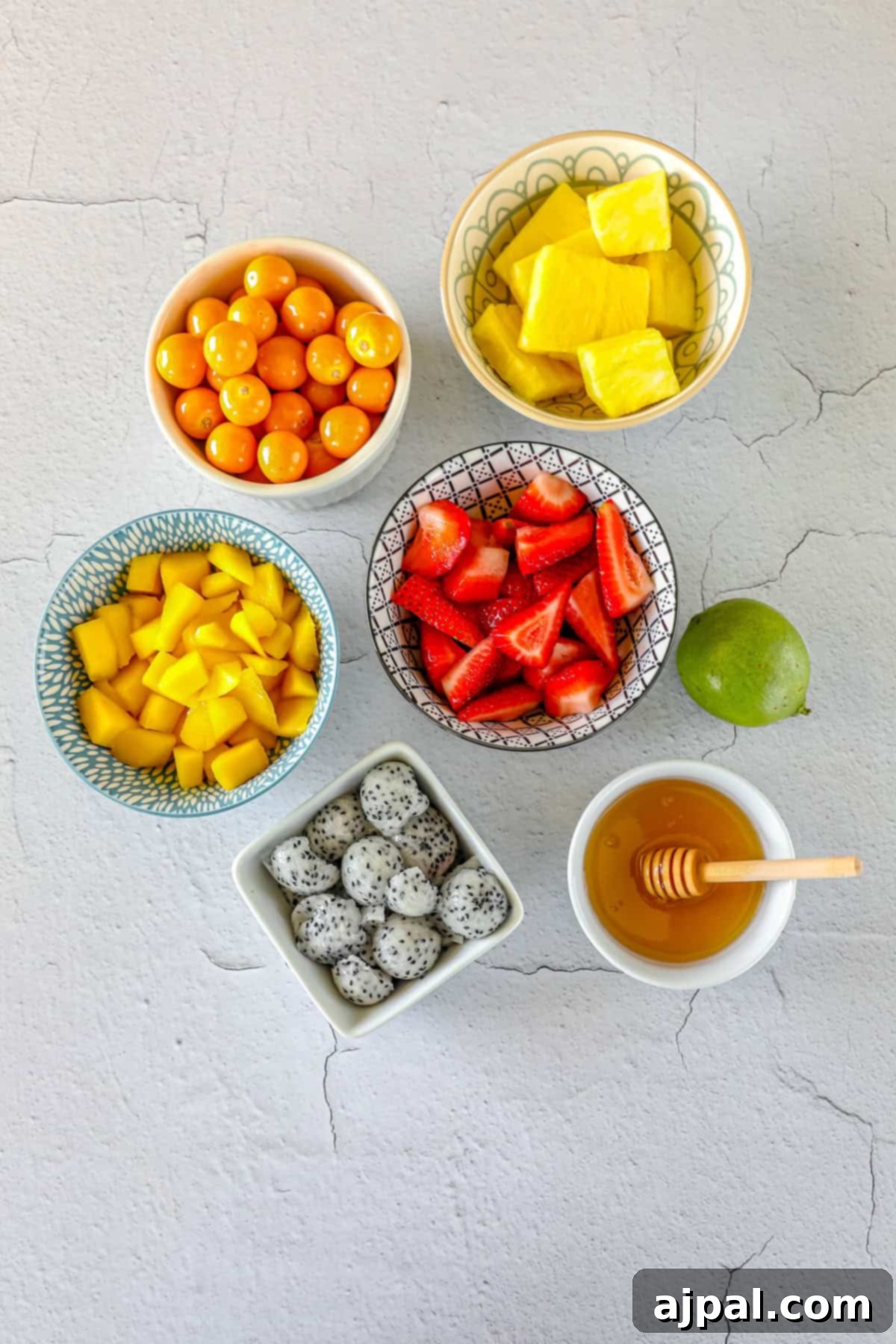 Paradise Fruit Medley 5 Assorted freshly cut tropical fruits including strawberries, pineapple, mango, and golden berries laid out on a cutting board, ready for assembly.