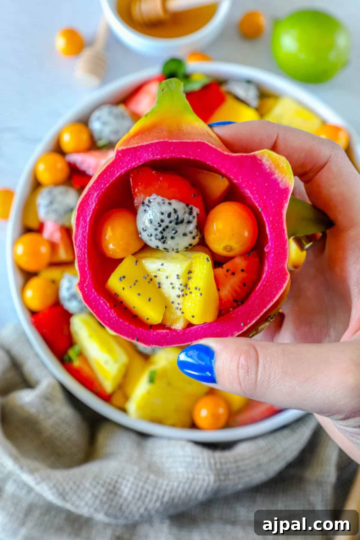 Paradise Fruit Medley 6 A large glass bowl filled with colorful tropical fruit salad, highlighted by a vibrant dragon fruit slice and various other fruits, ready to be served.