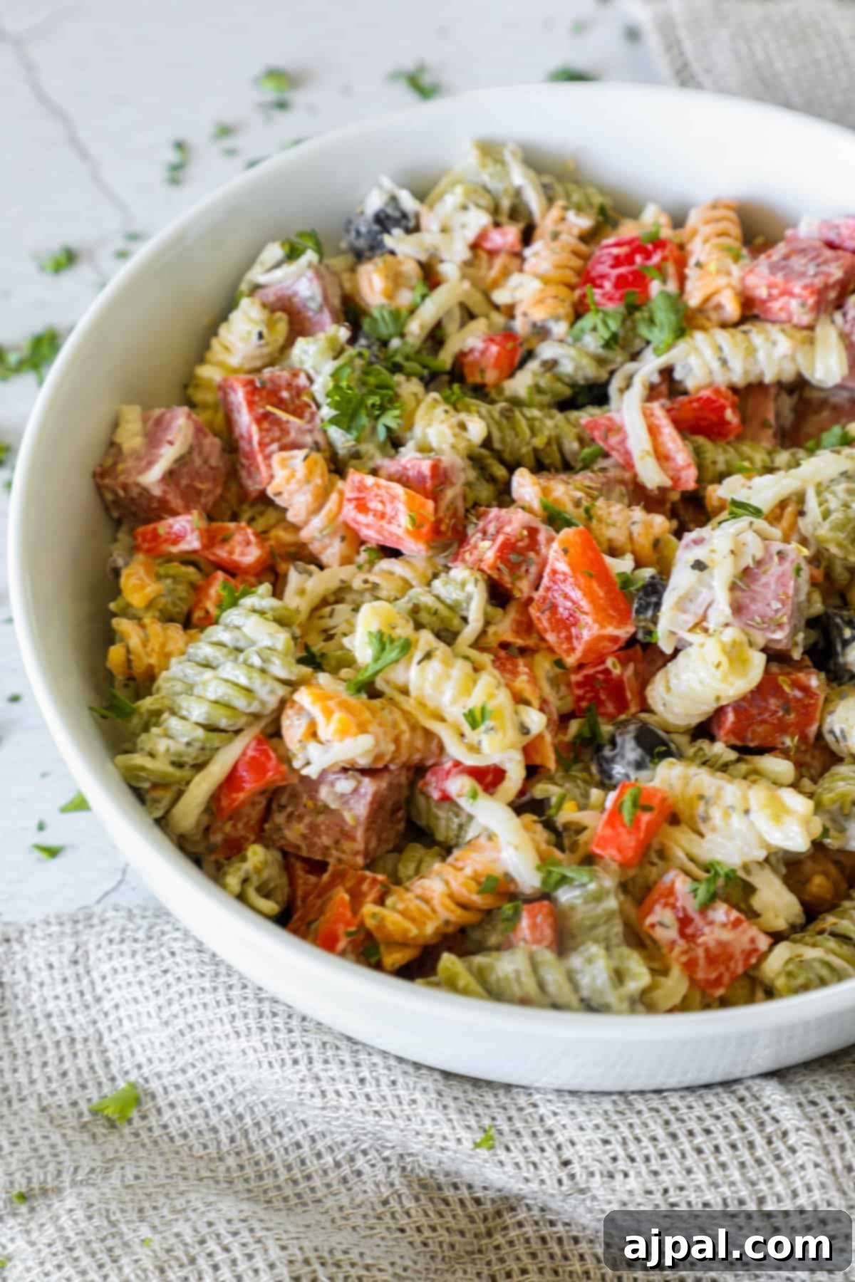 Creamy Italian Pasta Salad 8 A vibrant bowl of creamy Italian pasta salad with a serving spoon, showcasing the rich colors of the ingredients and inviting texture.