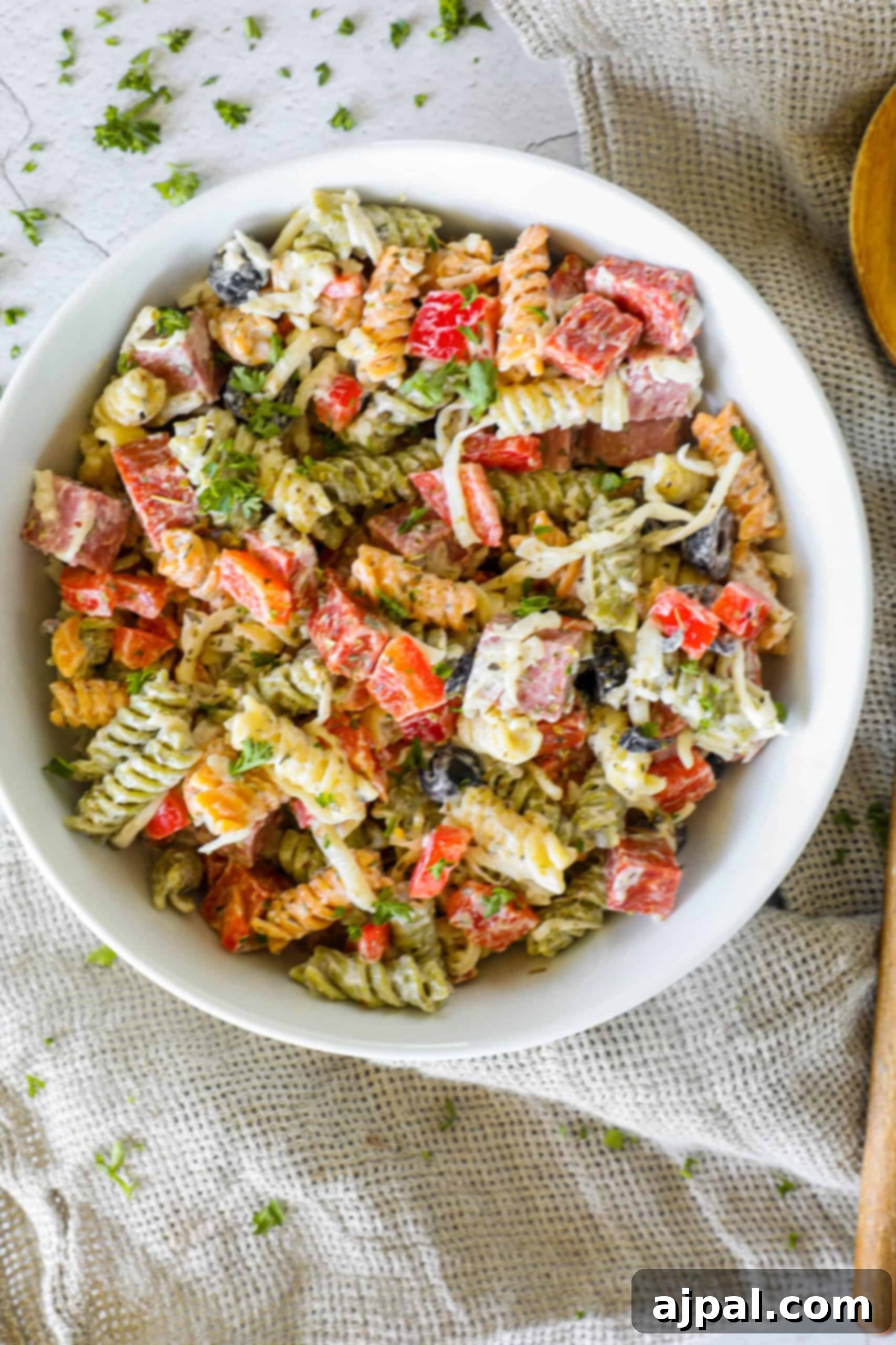Creamy Italian Pasta Salad 3 A close-up shot of creamy Italian pasta salad showcasing the texture of rotini pasta, diced salami, fresh mozzarella, and herbs, all coated in a rich dressing.