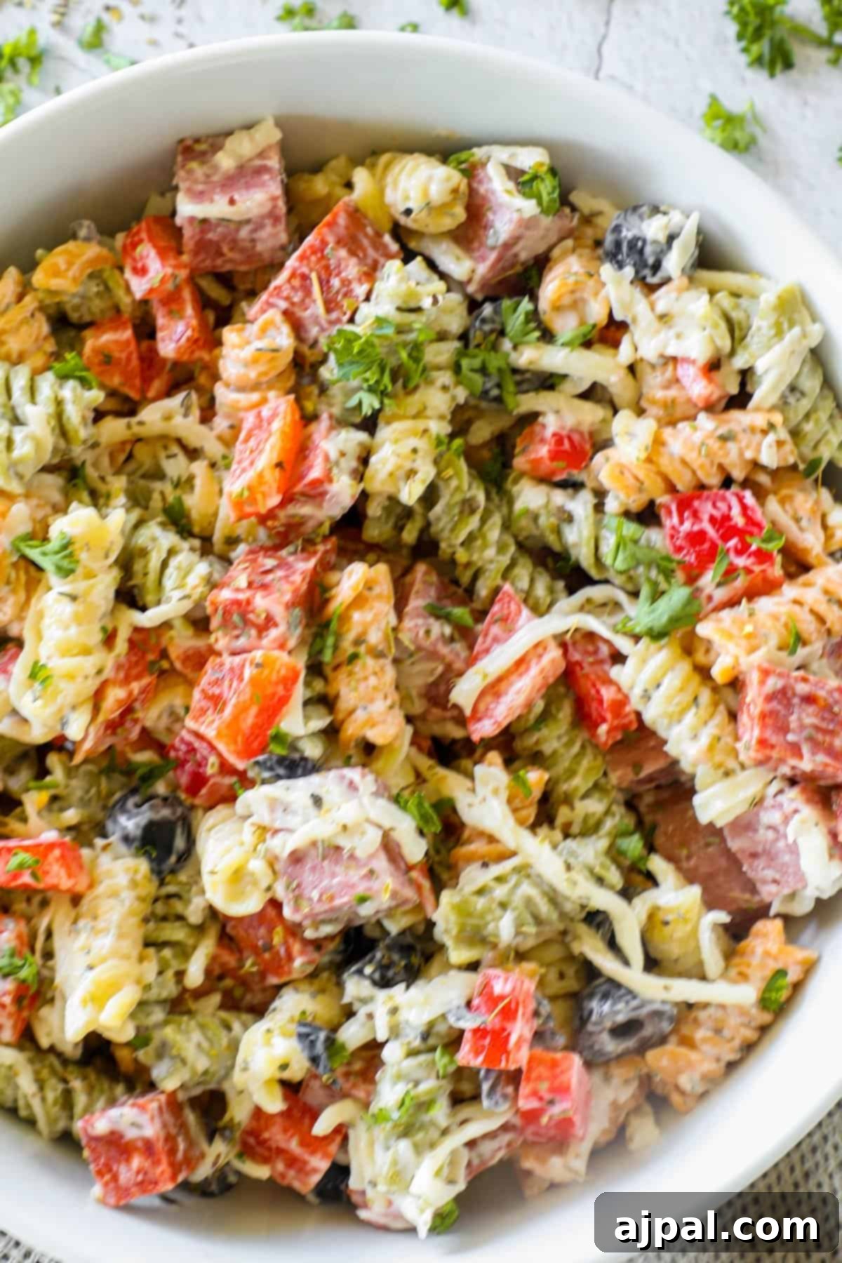 Creamy Italian Pasta Salad 4 An overhead shot of a large bowl of fresh, creamy Italian pasta salad with a serving spoon, highlighting the diverse ingredients and rich dressing.
