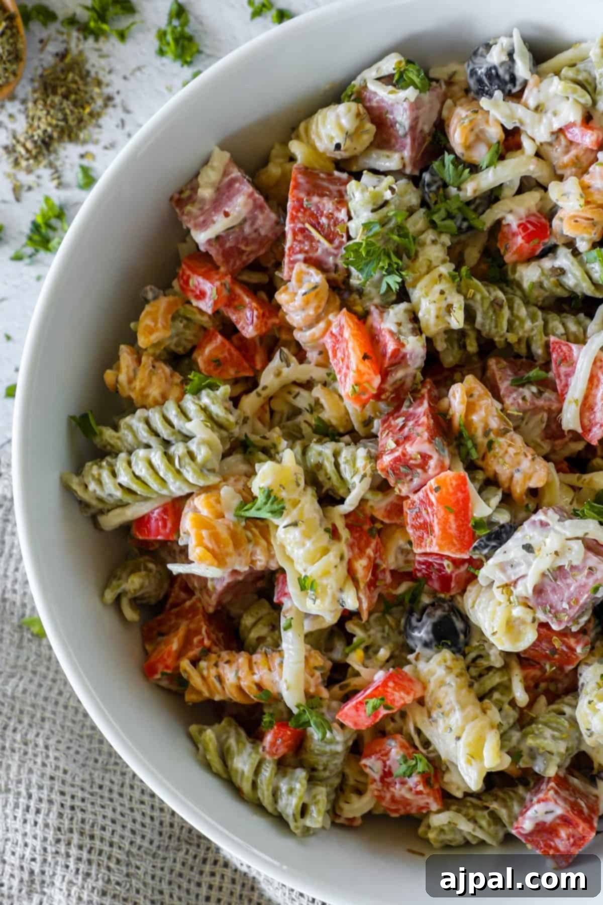 Creamy Italian Pasta Salad 6 A large serving bowl filled with creamy Italian pasta salad, garnished with fresh basil leaves and a sprinkle of black pepper, ready for enjoyment.