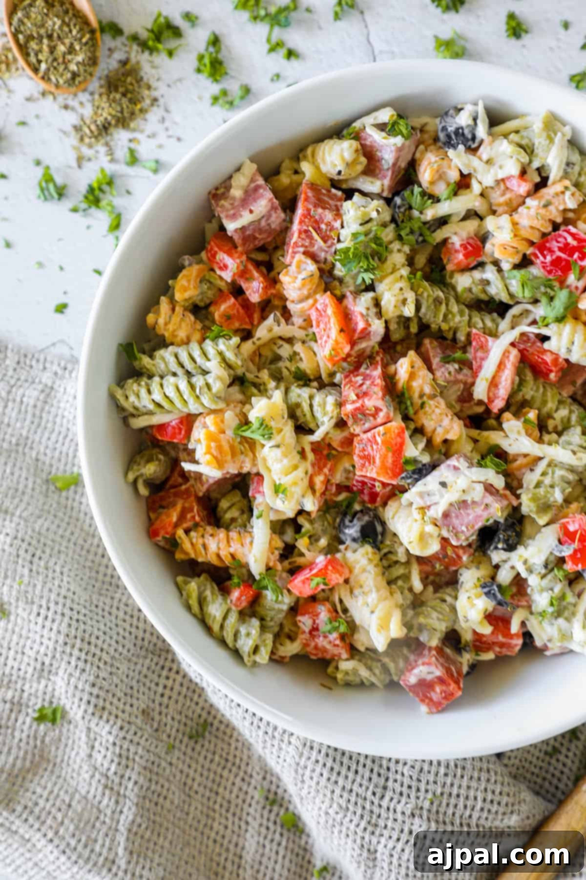 Creamy Italian Pasta Salad 7 A close-up of a serving of creamy Italian pasta salad with a fork, showing the rich coating of dressing and various ingredients.