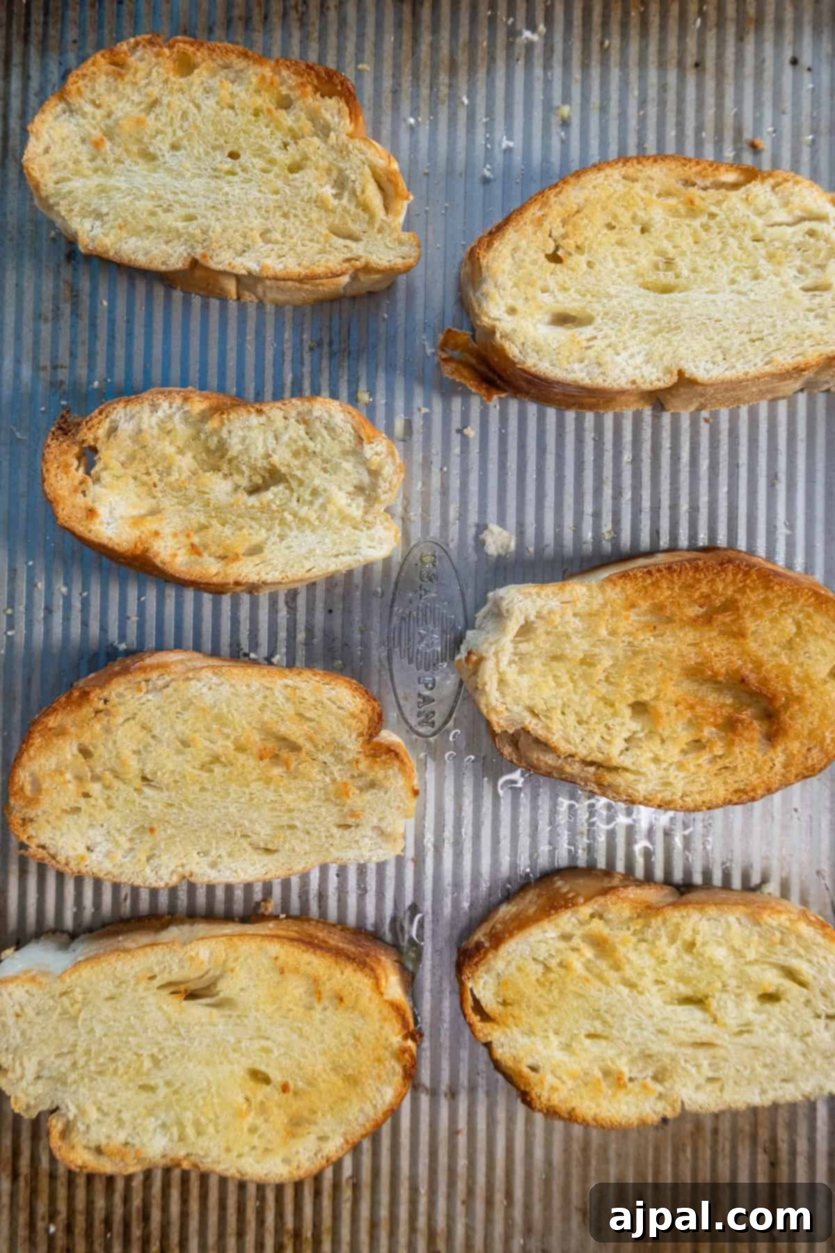 Freshly toasted bread slices being topped with the prepared grated tomato mixture.