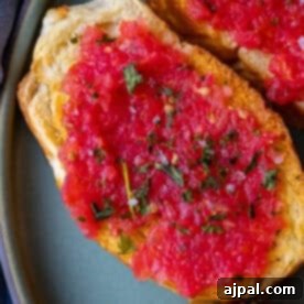 Two slices of bread topped with finely chopped tomatoes and herbs on a plate, this Pan Con Tomate is a classic Spanish recipe.