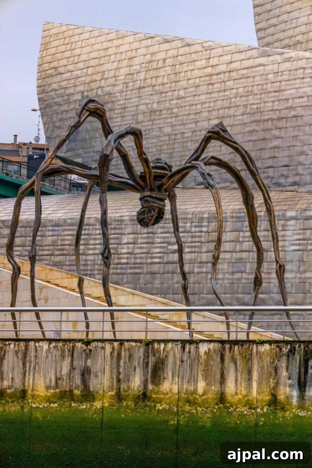 Bilbao: A Comprehensive Travel Guide 2 Large spider sculpture with long legs stands near an industrial building with a modern design. The sculpture appears to be made from metal and has a textured body and limbs, a defining feature of Bilbao's art scene.