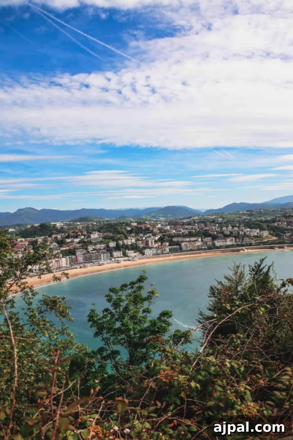 Panoramic view of San Sebastian from Monte Igueldo, showing La Concha Bay, the city, and mountains.