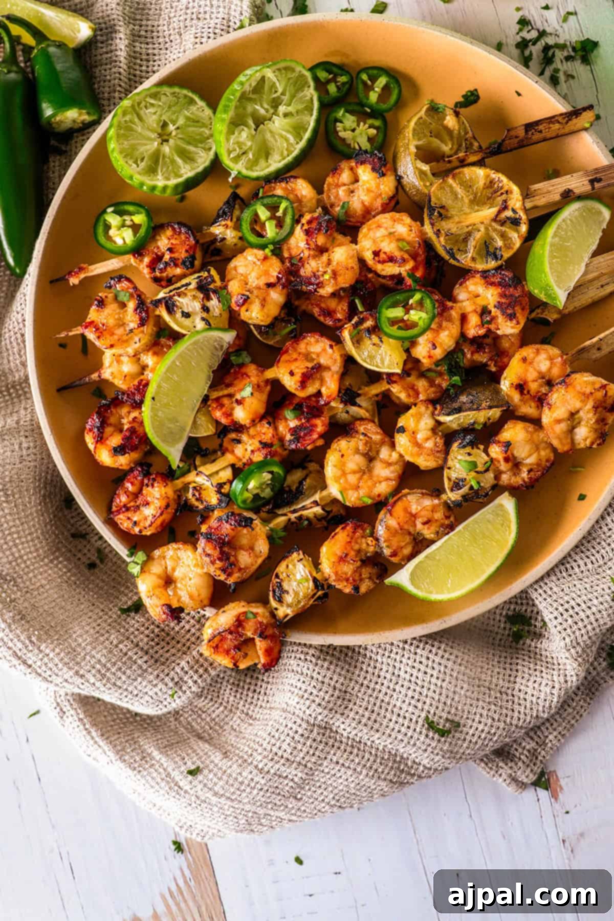 Zesty Margarita Grilled Shrimp 2 A vibrant plate of Margarita Grilled Shrimp skewers, garnished with fresh lime wedges, sliced green peppers, and charred lemon halves.