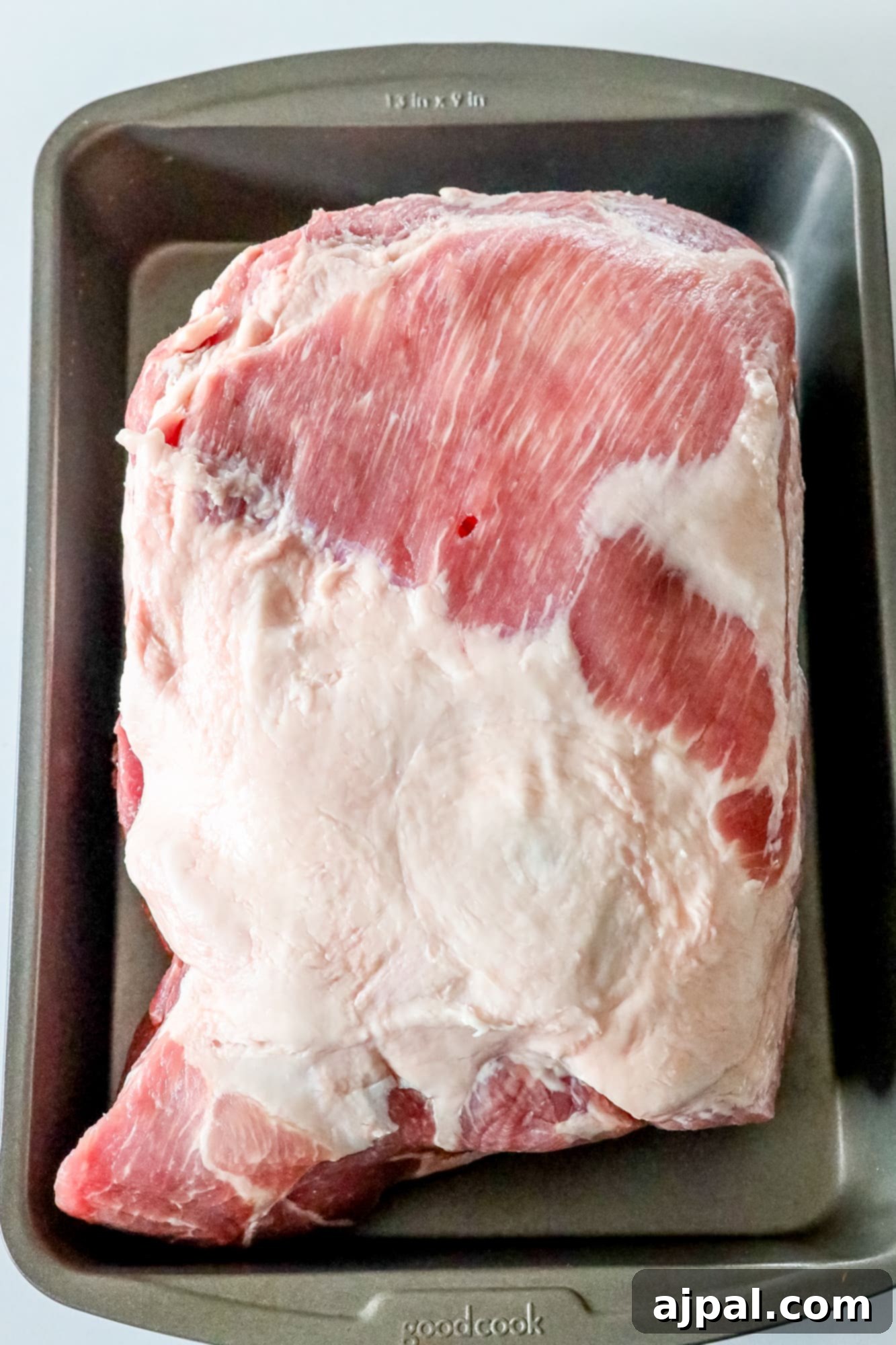 Picture of raw pork shoulder in a pan, ready for trimming and seasoning.