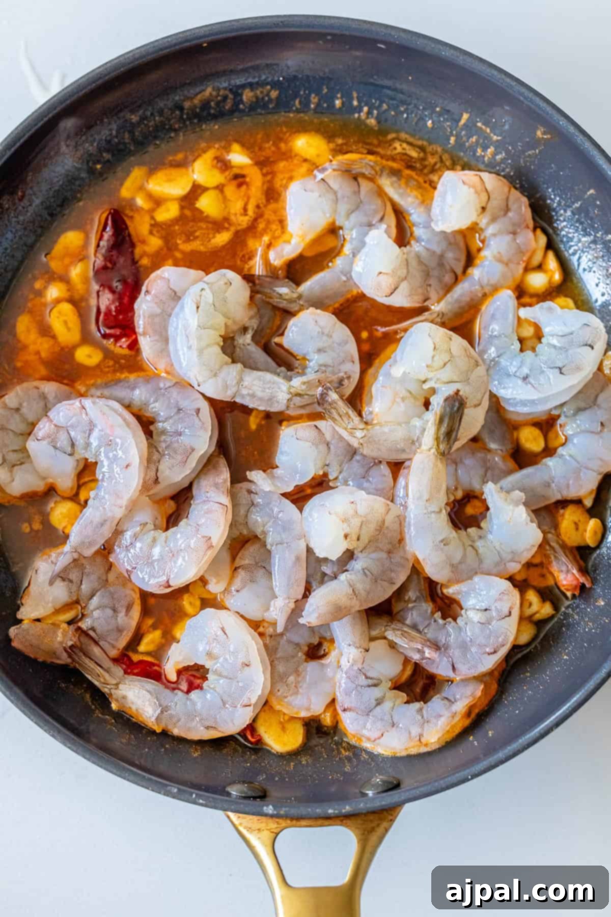 Prawns cooking in garlic and chili infused olive oil in a hot skillet.